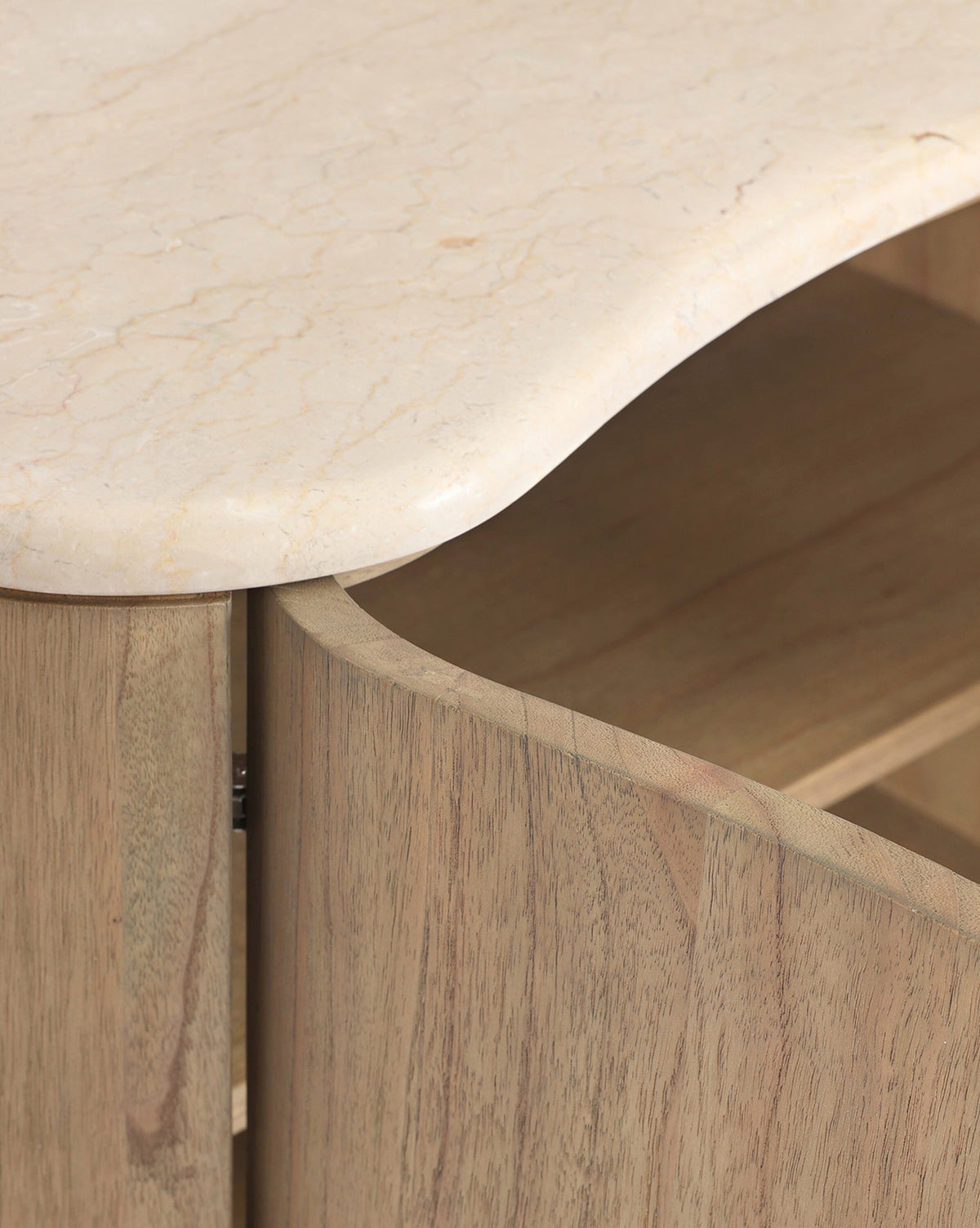 Close-up of the Gatlin Nightstand made from solid mindi wood, showcasing a curved edge and light, rounded marble top, by McGee & Co. A partially open cabinet door reveals convenient bedside storage inside.