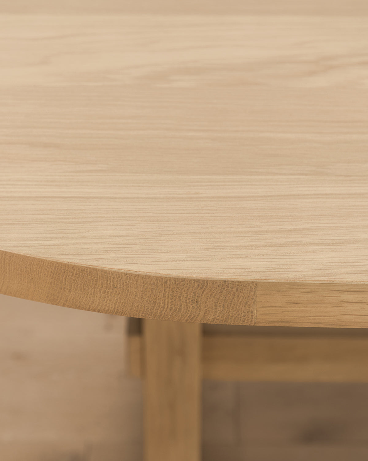 Close-up of the Giselle Oval Dining Table’s edge and surface, showcasing its smooth white oak finish, natural wood grain, and a glimpse of the table’s leg by McGee & Co.