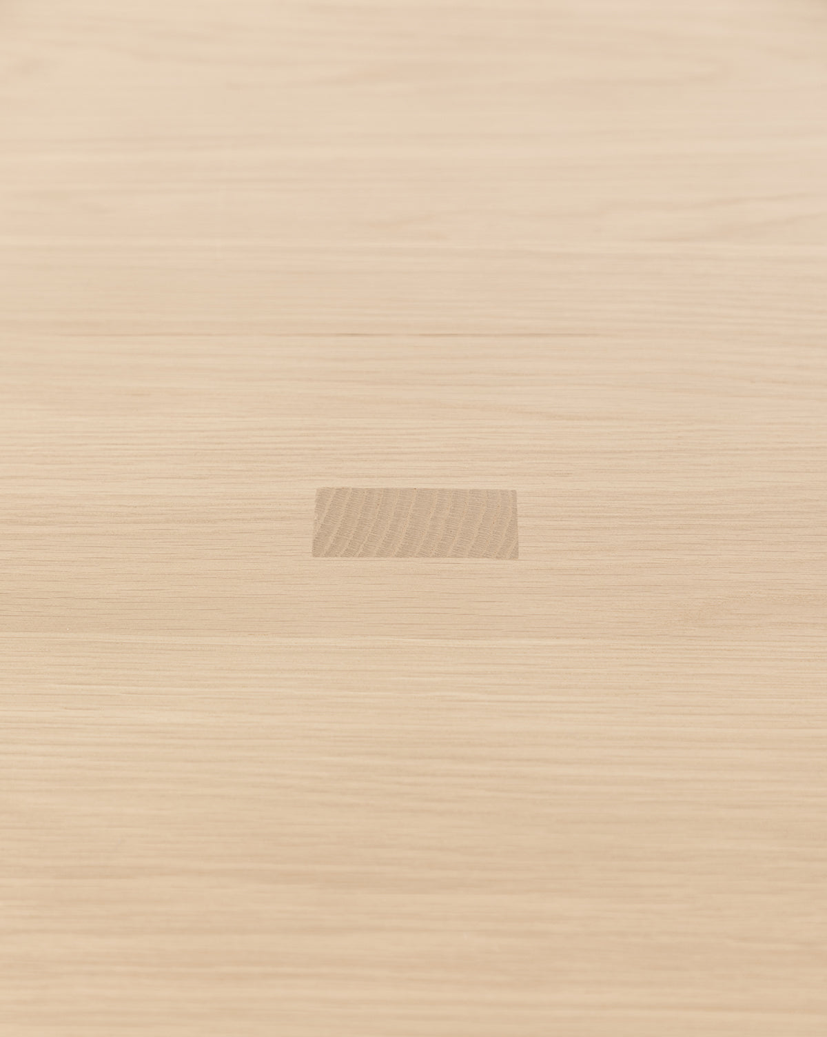 The Giselle Oval Dining Table features a light wood surface reminiscent of white oak, with a central rectangular patch where the wood grain subtly differs from the rest of the tabletop, by McGee & Co.