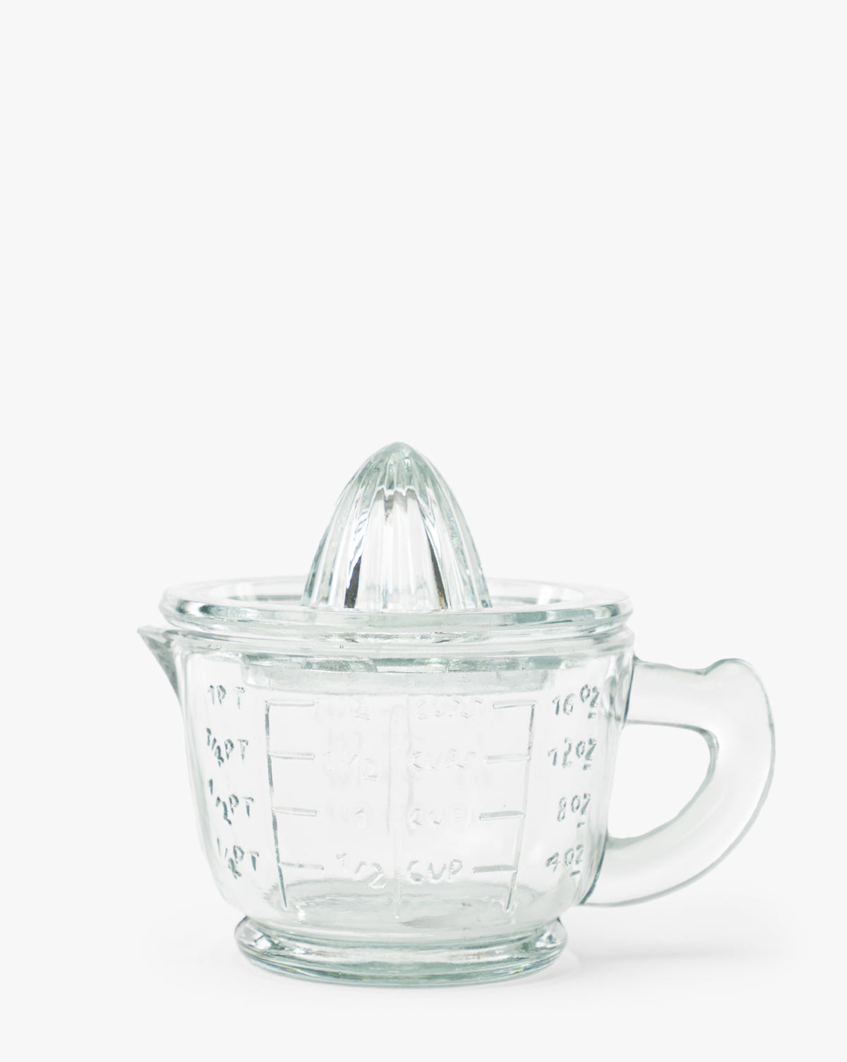 The Glass Juicer with Measuring Cup features a built-in reamer, handle, and measurement markings, shown against a plain white background by McGee & Co.