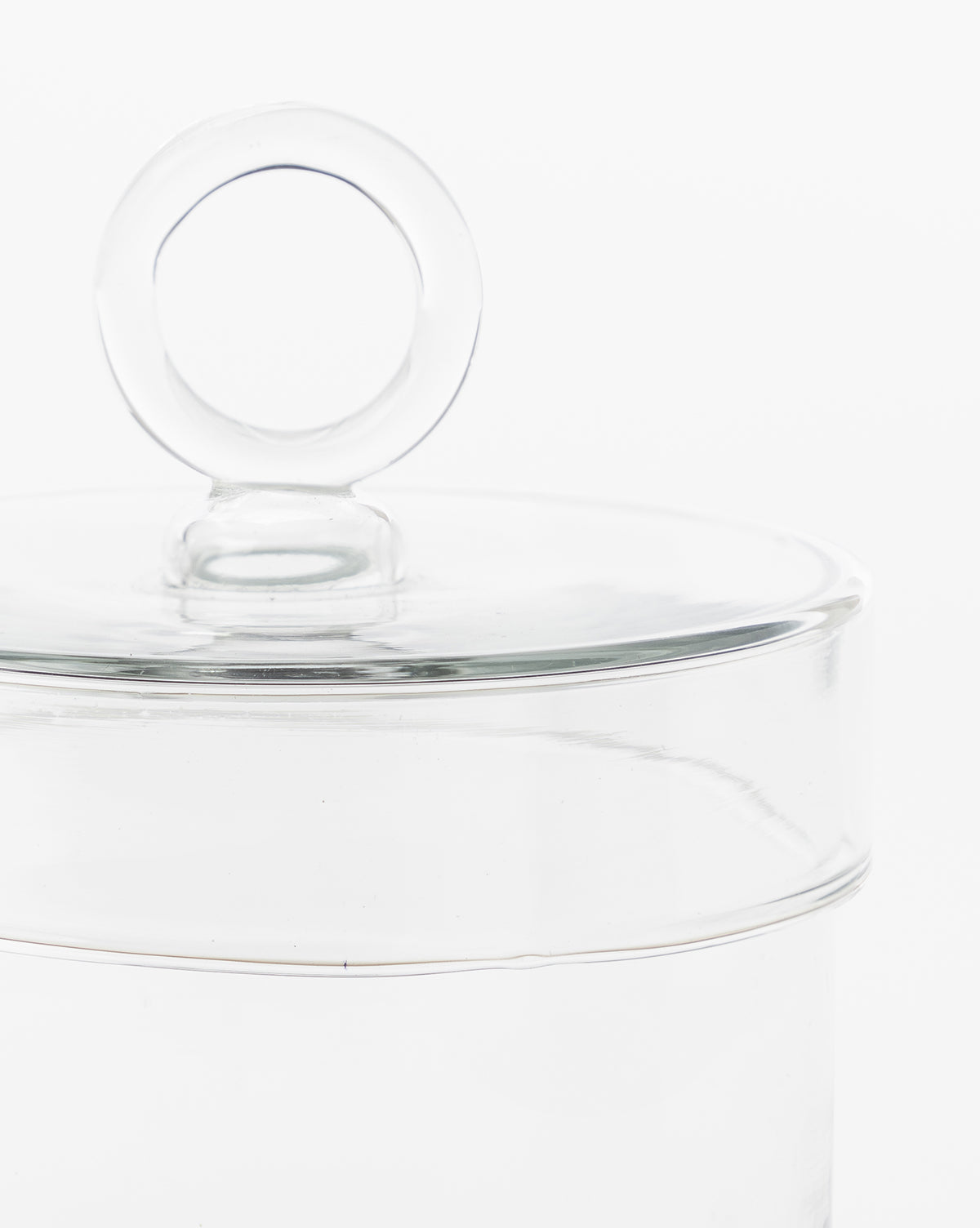 A close-up of the Glass Lidded Canister with a round lid handle, ideal for organizing small items on your bathroom countertop, shown against a white background.