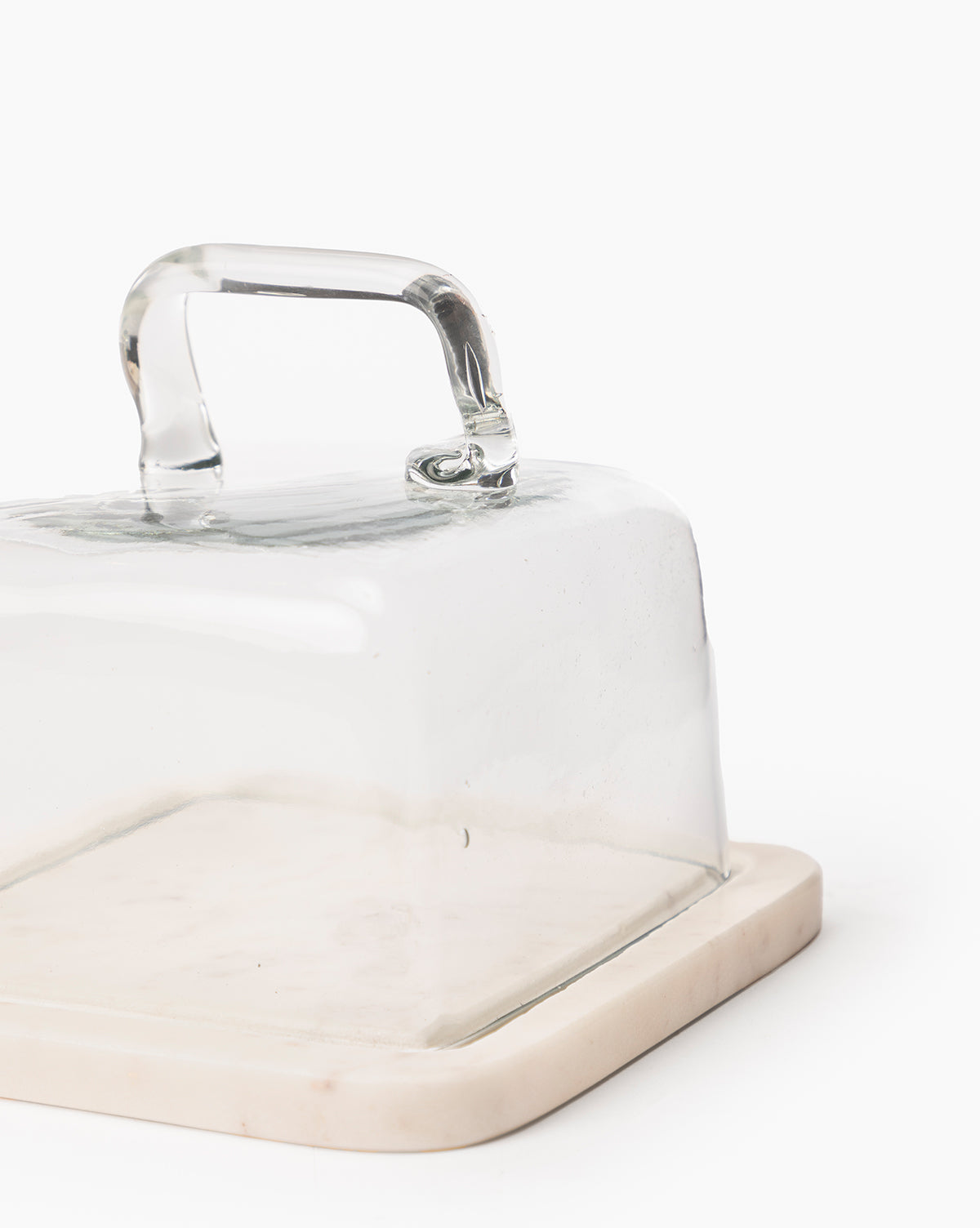 The Glass & Marble Cloche is a square butter dish with a clear glass lid and handle, featuring a sturdy marble base for modern elegance, displayed on a white background by McGee & Co.