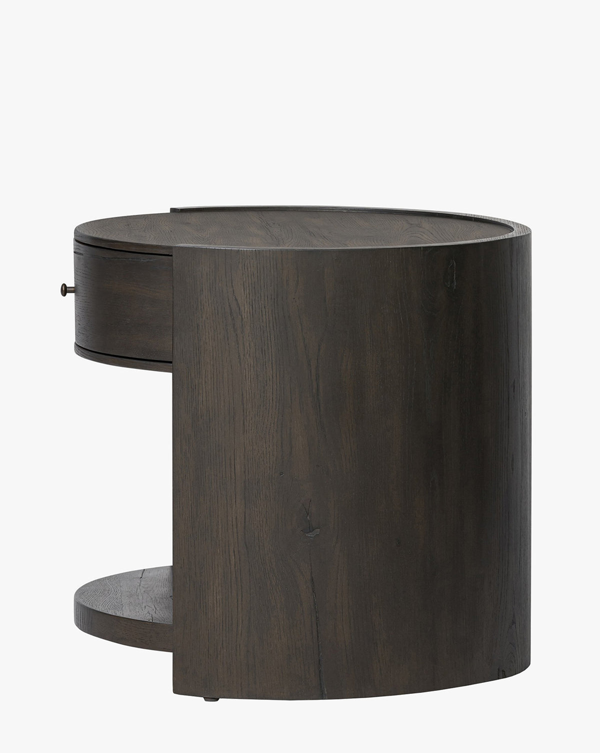 The Glenndon Oak Nightstand is a modern, round piece with a black-finished oak exterior, featuring one drawer and an open lower shelf, shown against a plain white background by McGee & Co.