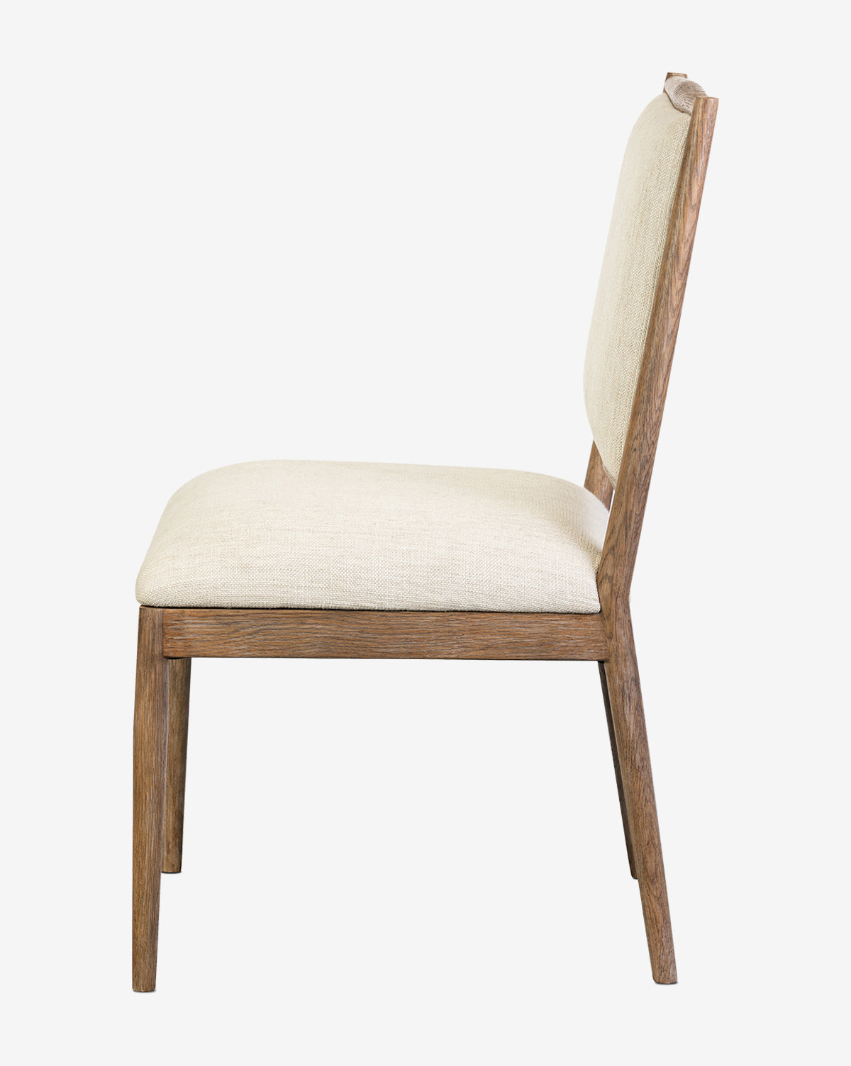 Side view of the Gomez Dining Chair, featuring solid oak construction, angled legs, and a light beige upholstered seat and backrest, displayed on a plain white background by McGee & Co.
