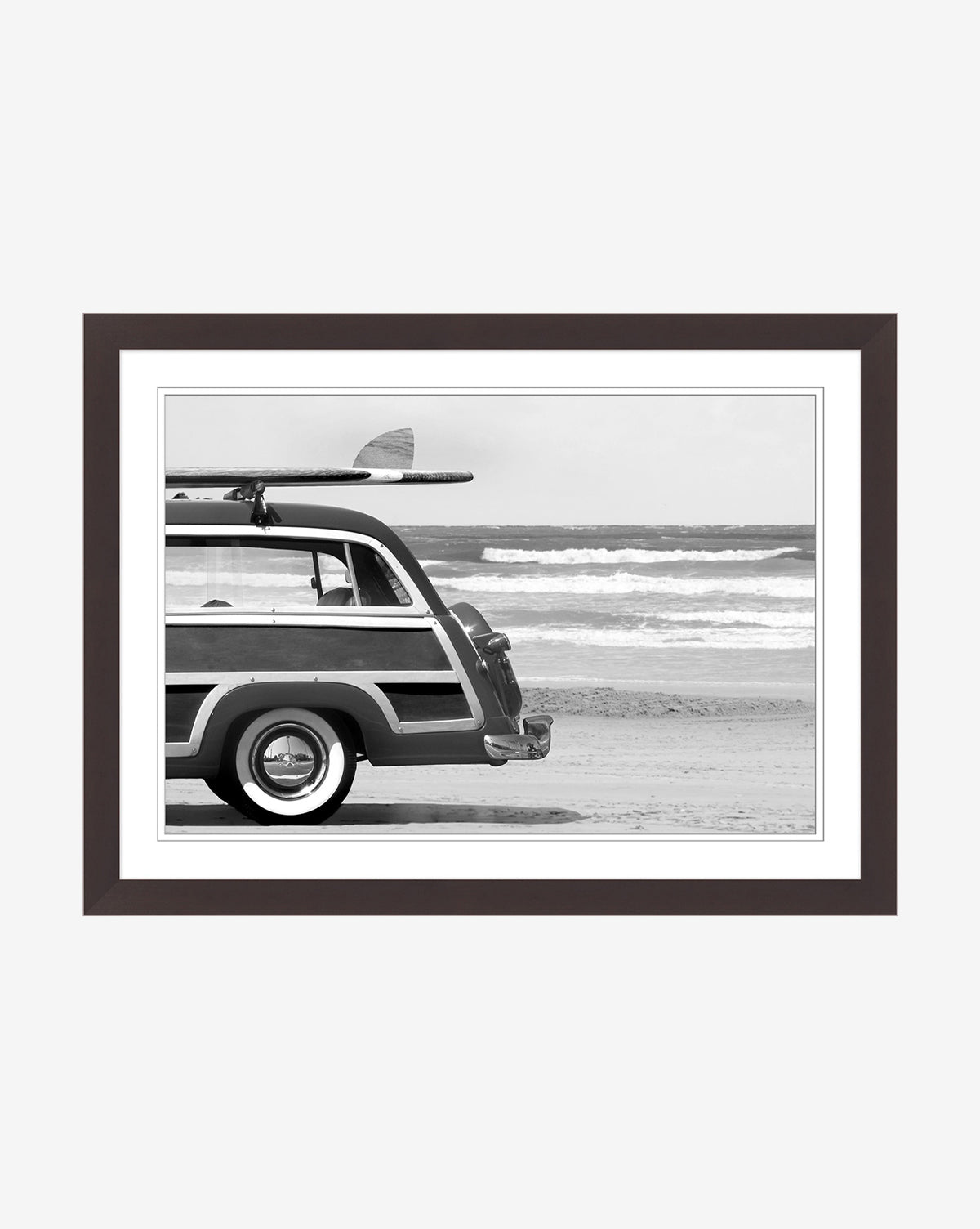 Gone Surfin wall art features a classic station wagon with a surfboard by the waves. Framed with a dark border, this black and white piece adds coastal cool style to your home decor.