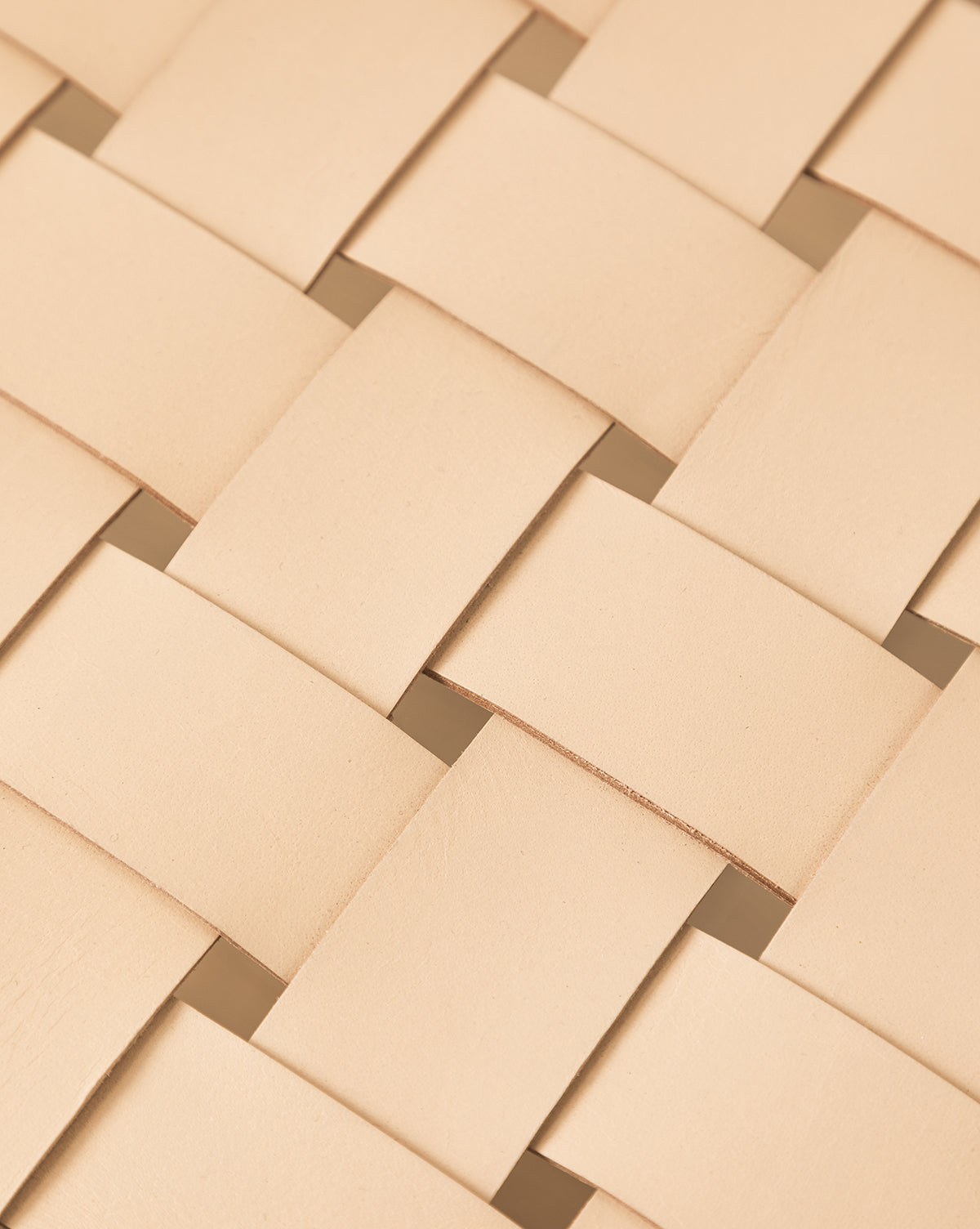 Close-up of the Greely Dining Chairs woven beige aniline-dyed leather, featuring overlapping flat strips in a crisscross design that showcases texture and natural color variations, reflecting expert craftsmanship, by McGee & Co.