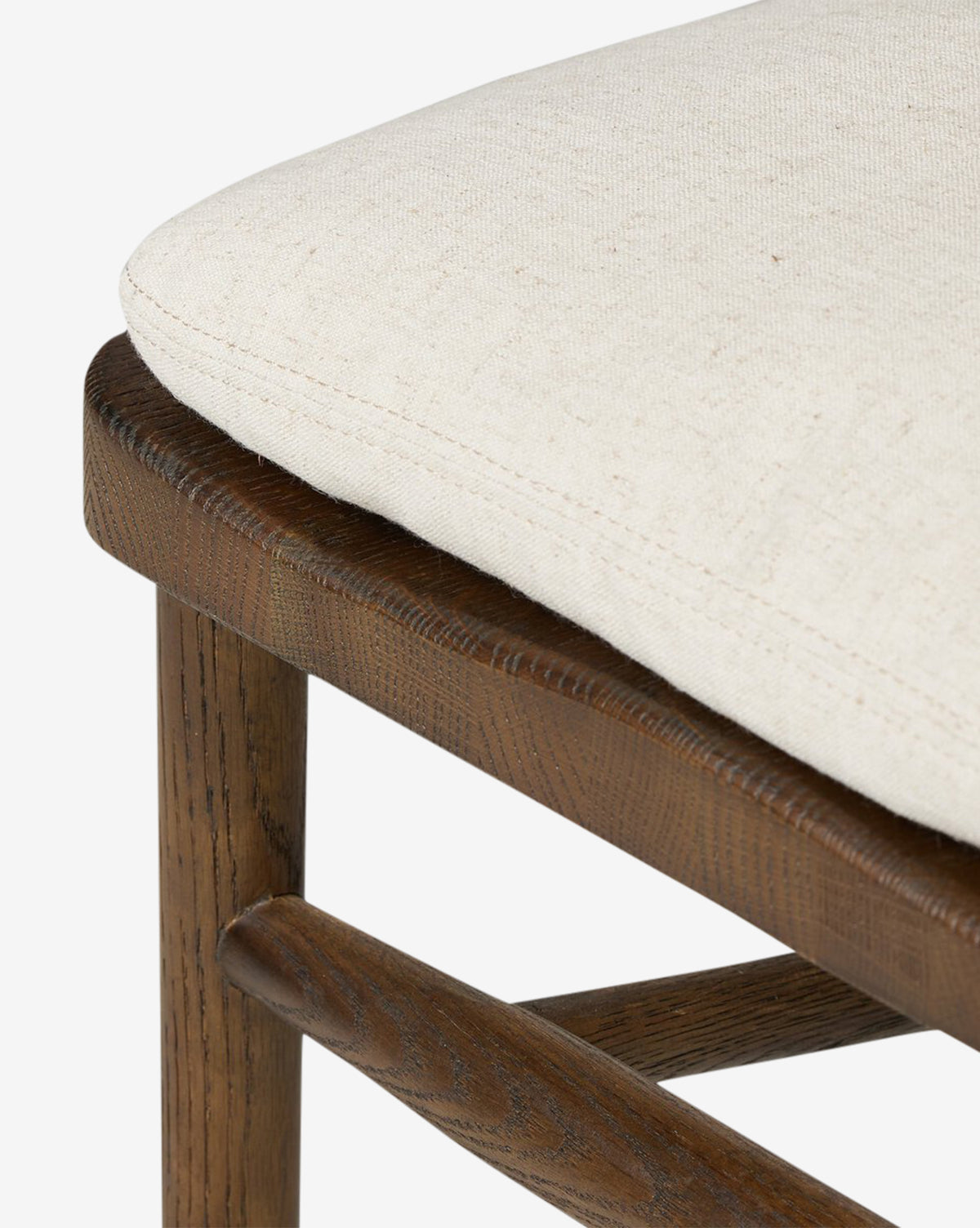 Close-up of the Hallow Chair, a rustic dining chair with a dark brown finish, beige upholstered cushion, and visible wood grain on the frame and crossbar, by McGee & Co.