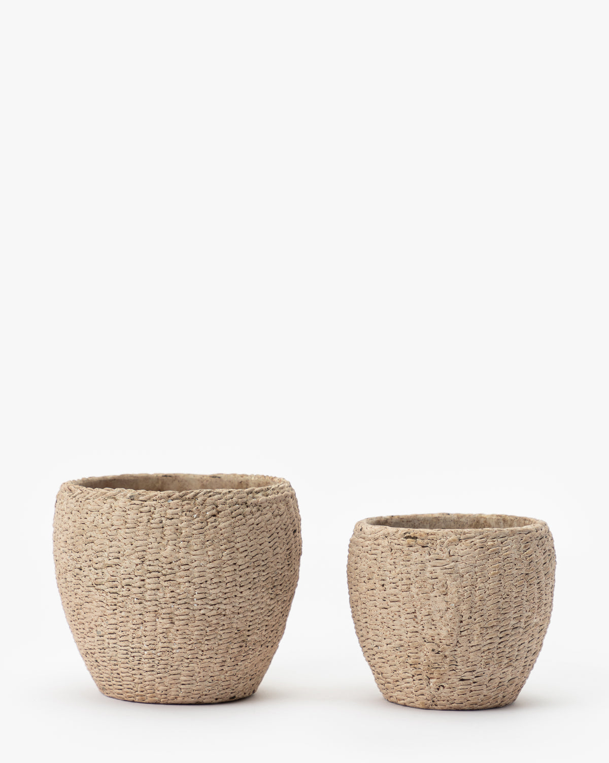 Two round Halston Cement Planters with a textured finish are placed side by side on a white background; one is larger than the other, making them perfect for stylish storage or displaying plants.