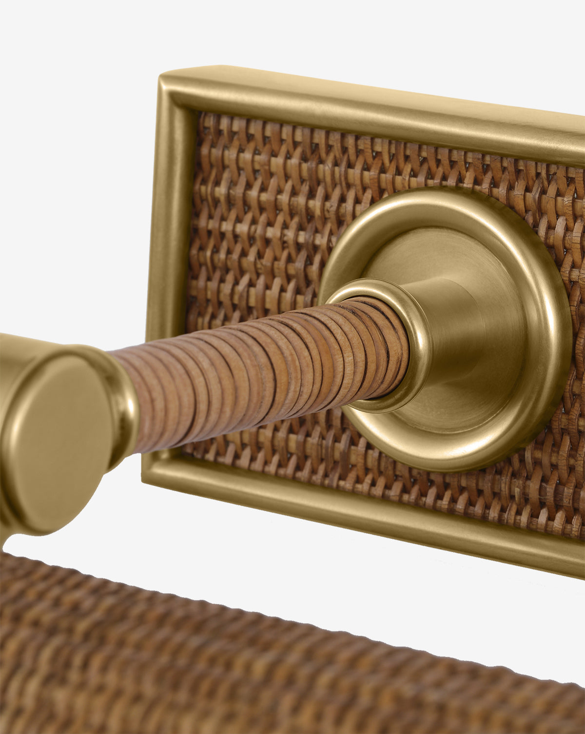 Close-up of the Halwell Picture Light illuminating a brass door handle with a woven rattan backplate and grip, highlighting the elegant mix of metallic and natural materials, by McGee & Co.