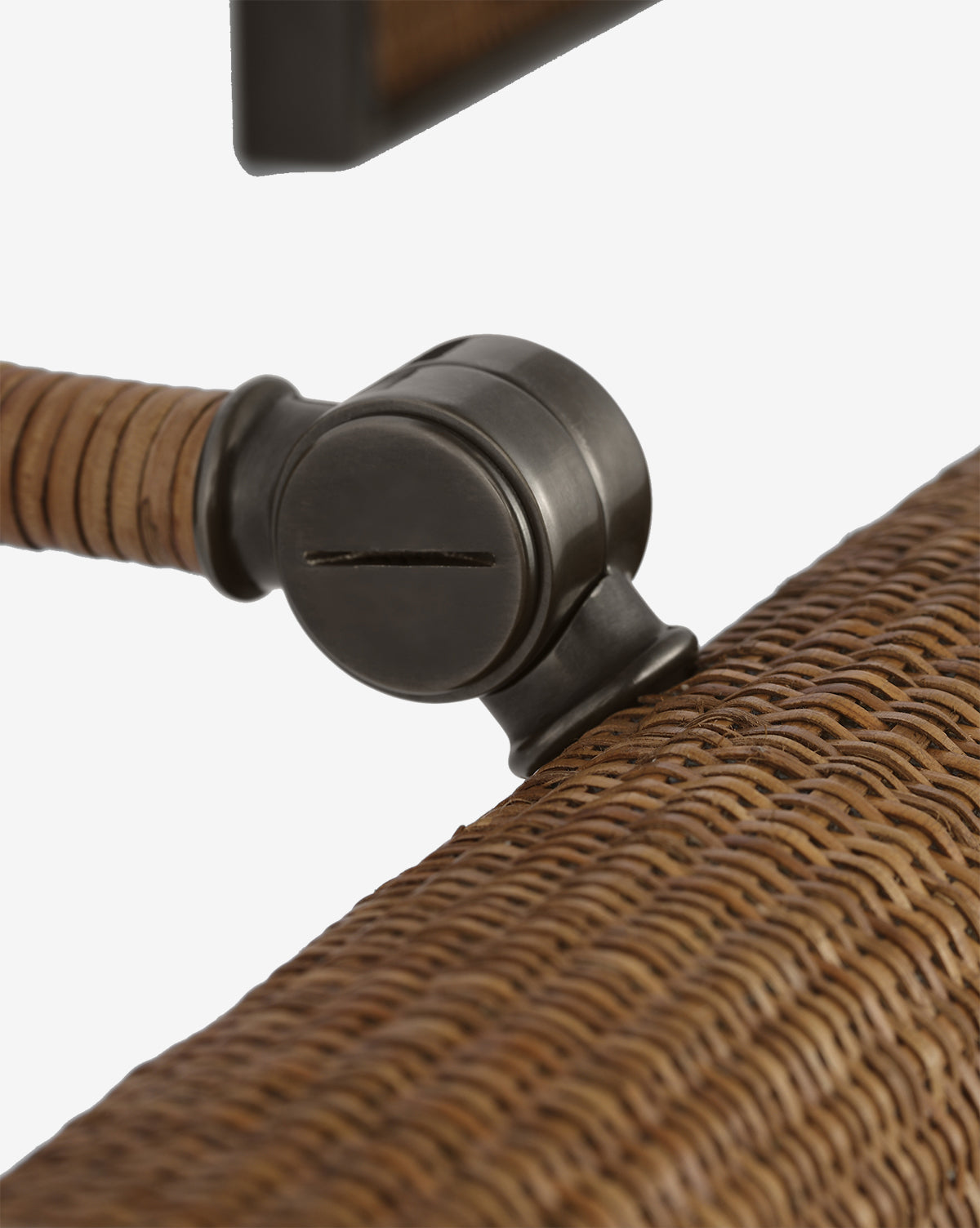 Close-up of the Halwell Picture Light: a black metal adjustable clamp attached to a brown woven rattan chair frame, ideal for securing artwork or picture lighting, featuring a wrapped detail on the arm, by McGee & Co.