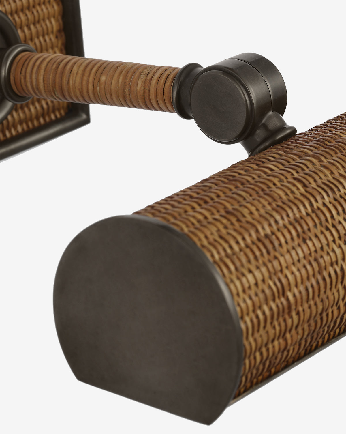 Close-up of the Halwell Picture Light, a wall-mounted fixture featuring a woven rattan-style shade and dark metal accents. The cylindrical shape with rounded ends is perfect for lighting artwork against any white backdrop, by McGee & Co.