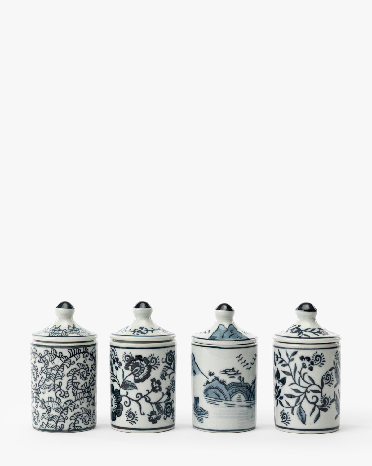 The Hand-Painted Spice Jars (Set of 4) features white ceramic jars with blue lids, adorned with detailed floral and landscape designs. These artisanal kitchen accents are displayed in a row against a plain white background, by McGee & Co.