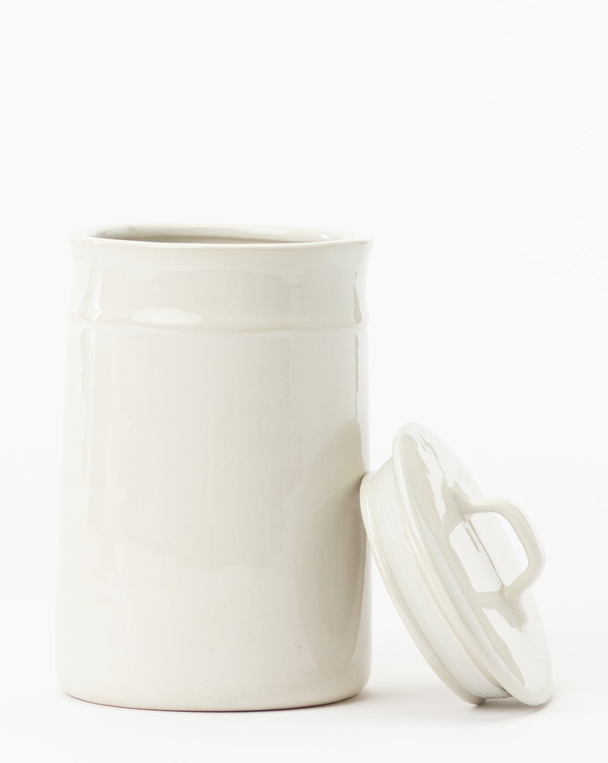 The Handled Ceramic Canister is a white, cylindrical ceramic jar with a matching lid and a glossy finish—ideal for contemporary kitchens.