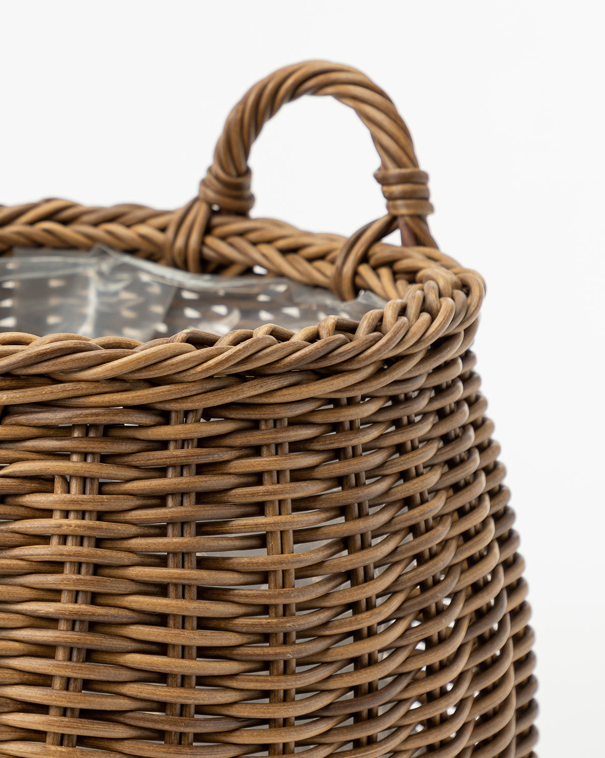 Close-up of the Handled Planter Basket, featuring a brown poly-rattan weave, twisted rope handle, and a clear plastic liner—charming and ideal for displaying indoor plants against a white background.