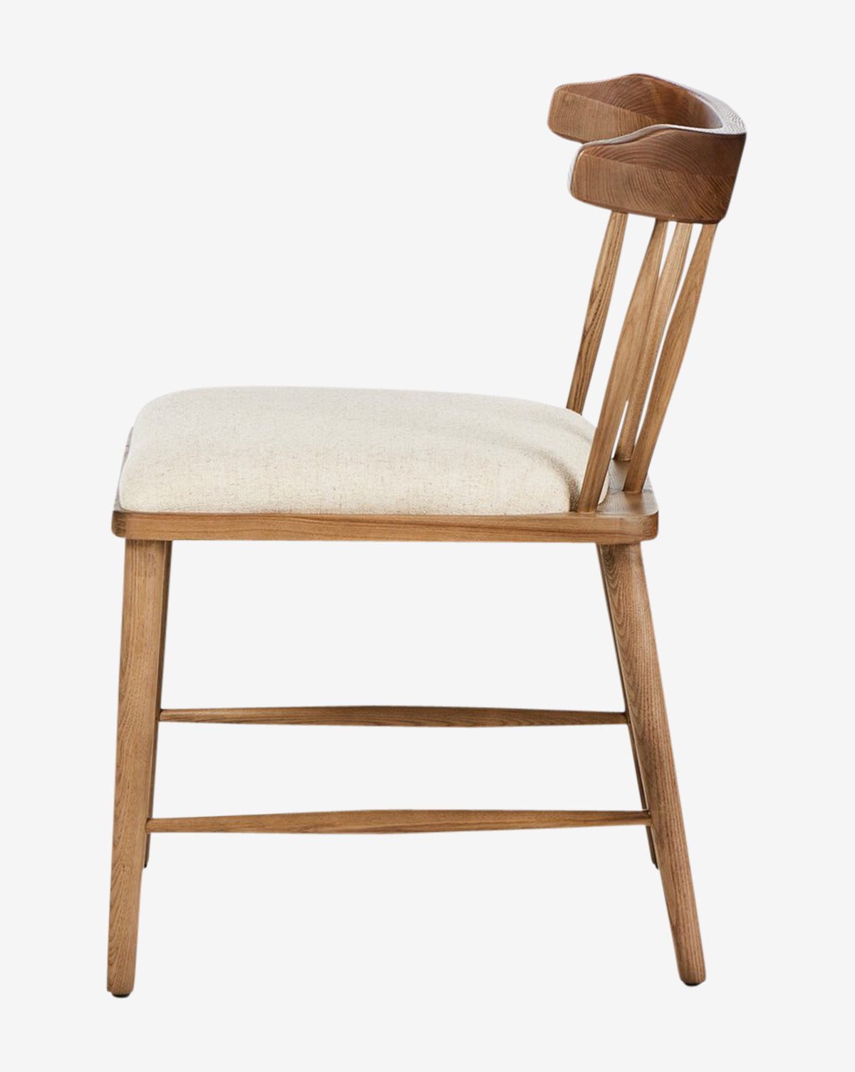 Side view of the Harper Dining Chair, showing its solid ash frame, light beige upholstered seat, curved wooden backrest with slender spindles, and simple angled legs that accentuate a minimalist design, by McGee & Co.
