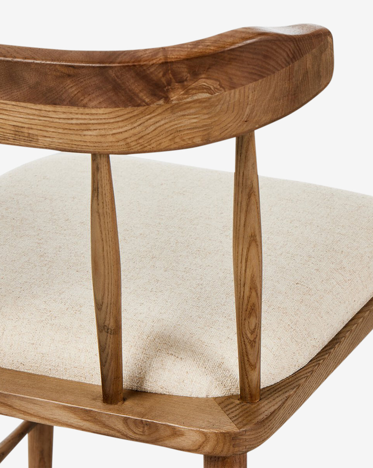 Close-up of the Harper Dining Chair, made from solid ash with a curved backrest and two vertical supports, and finished with a light beige upholstered seat, by McGee & Co.