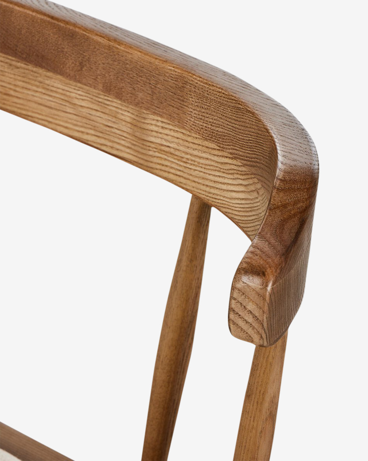 Close-up of the Harper Dining Chair shows its curved solid ash backrest with smooth grain, two vertical supports, a light finish, and an upholstered seat for comfort, set against a plain white background by McGee & Co.