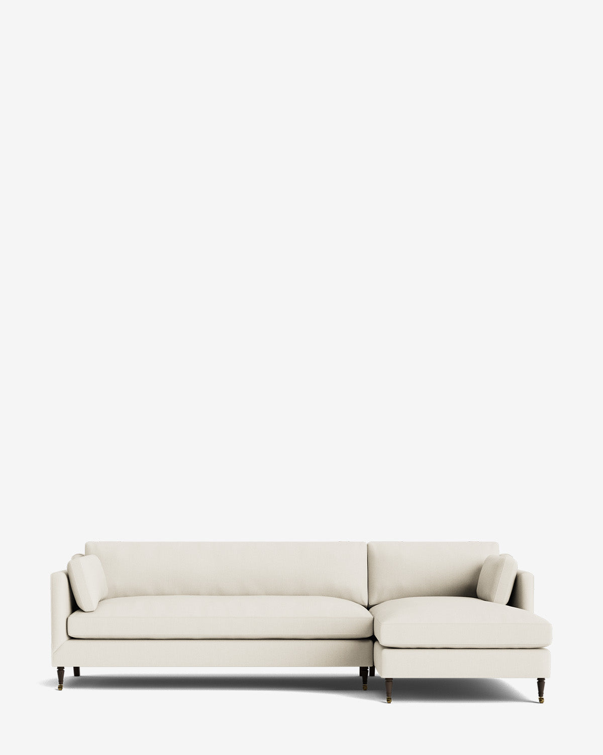 The Haverford Upholstered Right Chaise Sectional features light beige fabric, a right chaise, two matching bolster pillows, and dark wooden legs. This customizable sofa combines comfort and style for any living space, by McGee & Co.