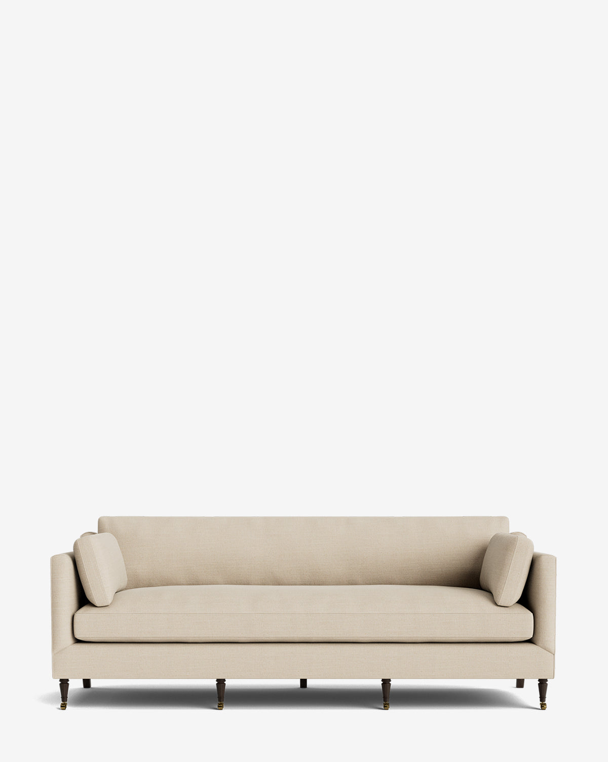 The Haverford Upholstered Sofa 90 is a beige, modern three-seater featuring clean lines, two matching cylindrical bolster pillows, and dark wooden legs with brass castors—handcrafted and set against a plain white background by McGee & Co.