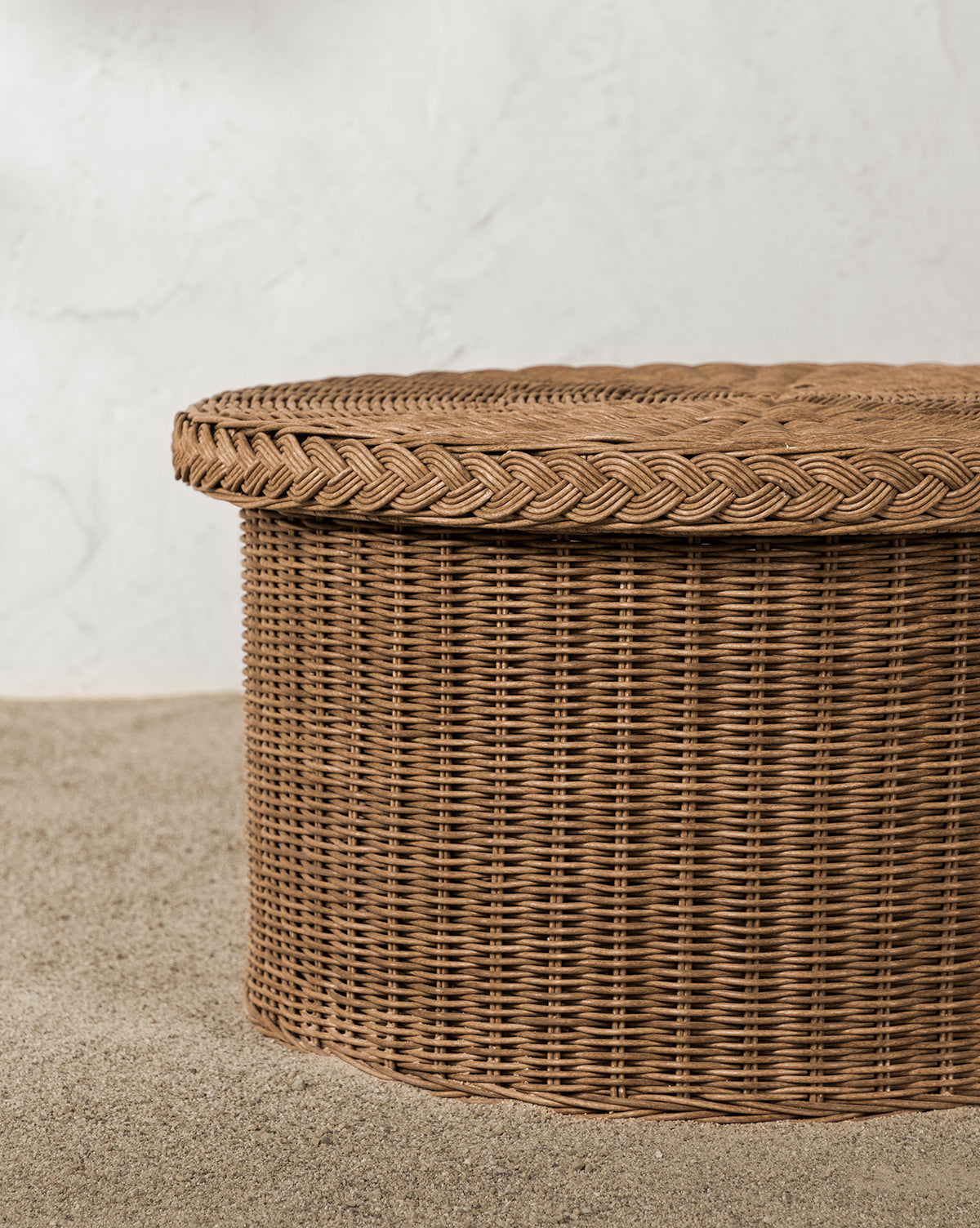 Close-up of the Haviland Coffee Table, featuring weather-resistant, tightly woven light brown wicker, set against a backdrop of small, light-colored pebbles, by McGee & Co.