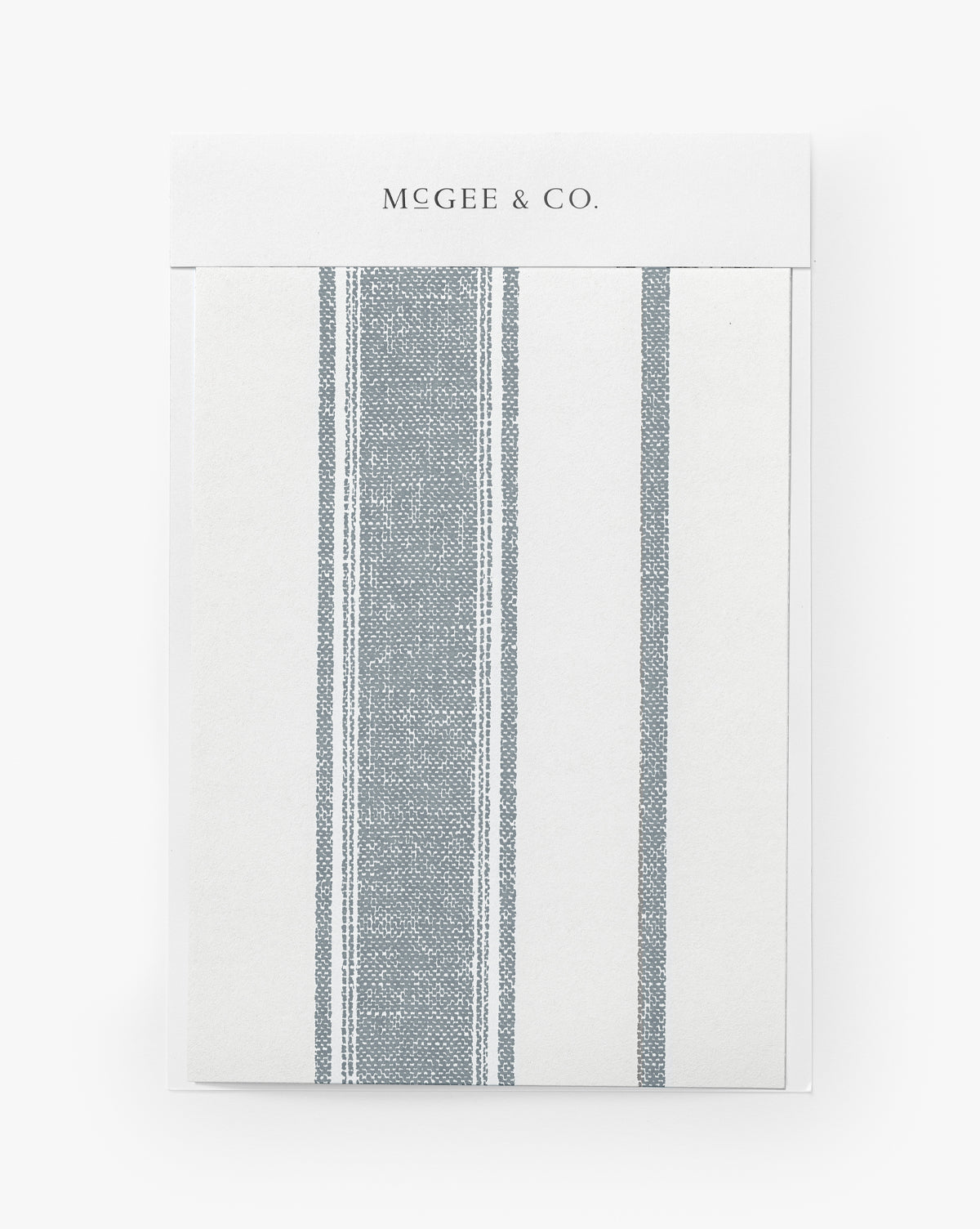 The Hawes Stripe Wallpaper Swatch features a simple vertical stripe design on the front, reminiscent of woven-inspired patterns and labeled as Hawes Stripe Wallpaper, by McGee & Co.