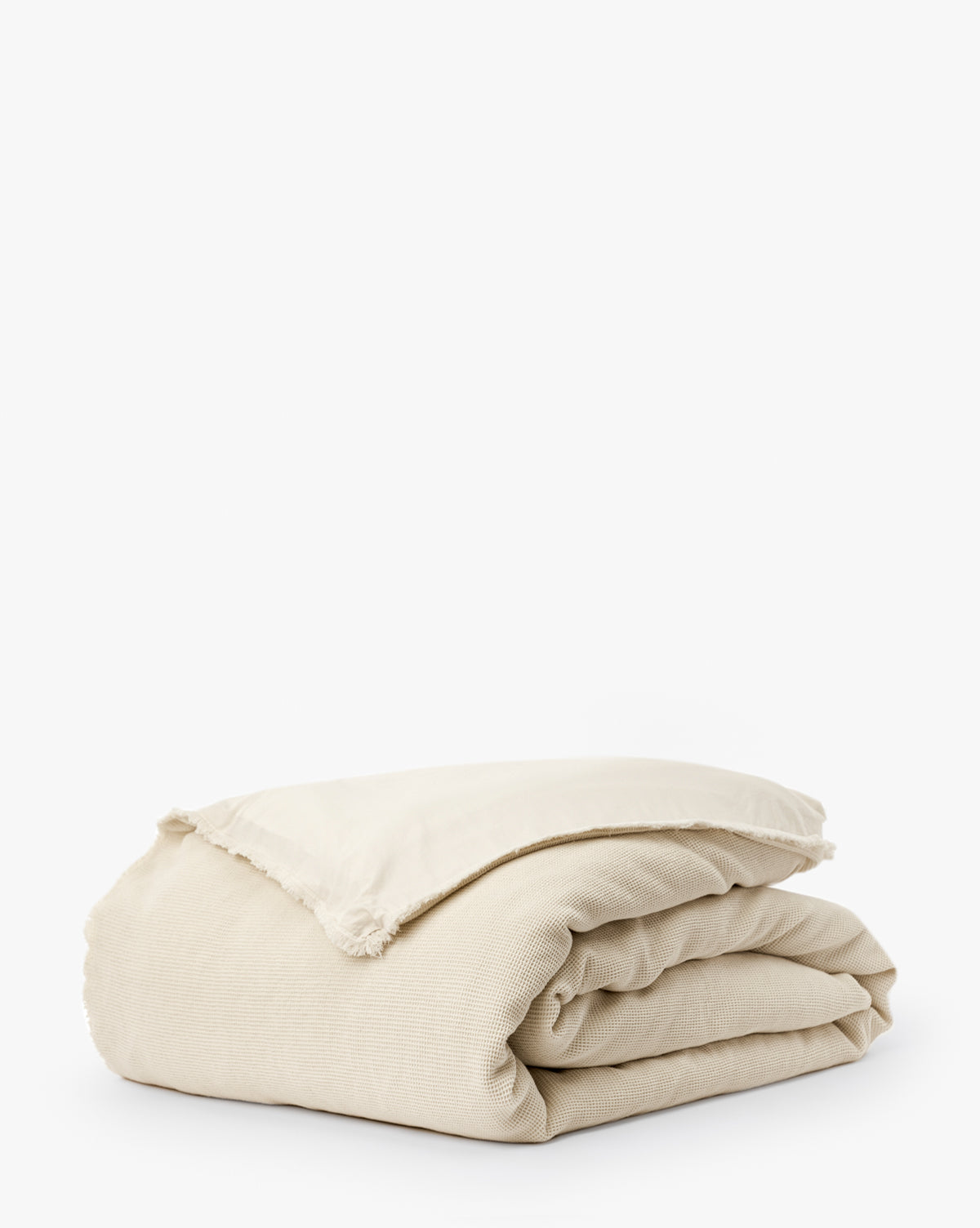 The Helene Waffle Duvet Cover, in light beige with frayed edges and a textured finish, is neatly folded and displayed on a plain white background.