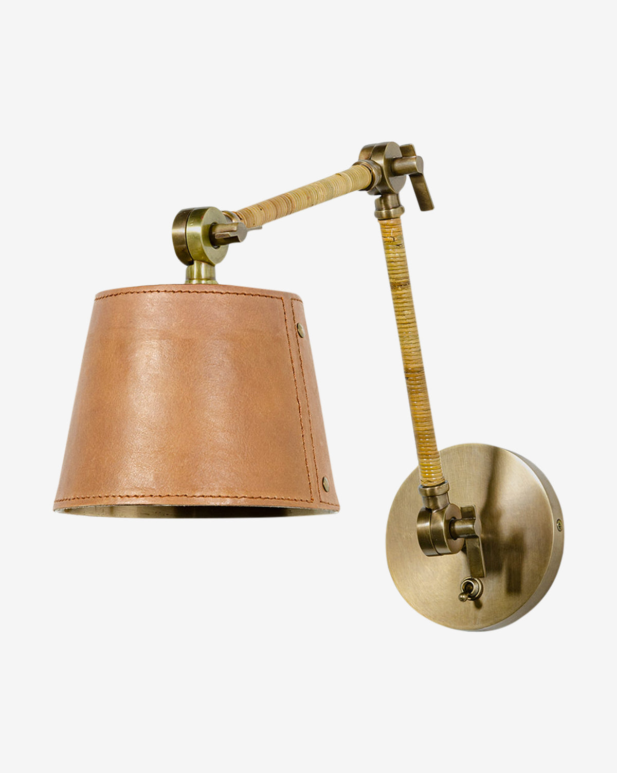 The Palecek Hendrick Articulating Sconce features a brass frame with an adjustable neck and a light brown leather shade, displayed against a plain white background. McGee & Co.