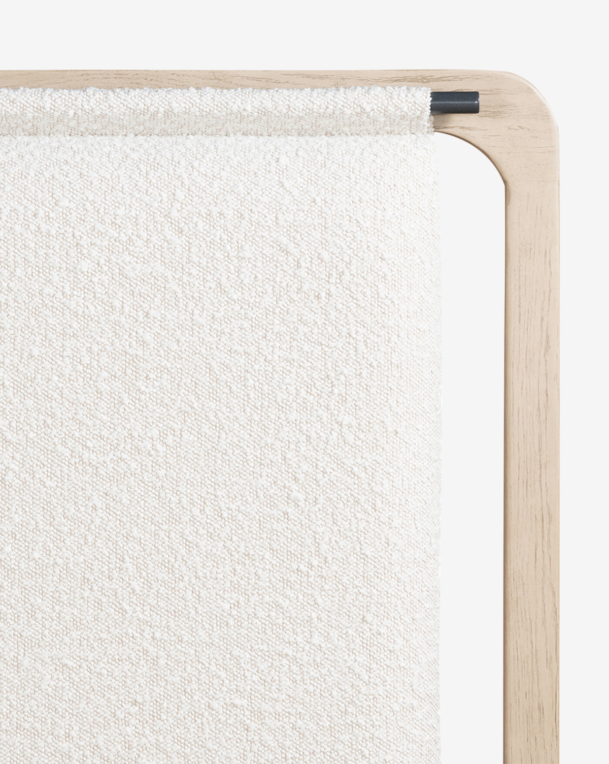 A close-up of a light wooden frame with textured off-white fabric draped over it, secured by a black rod—an elegant, modern detail inspired by the refined design of the Hensley Bed.
