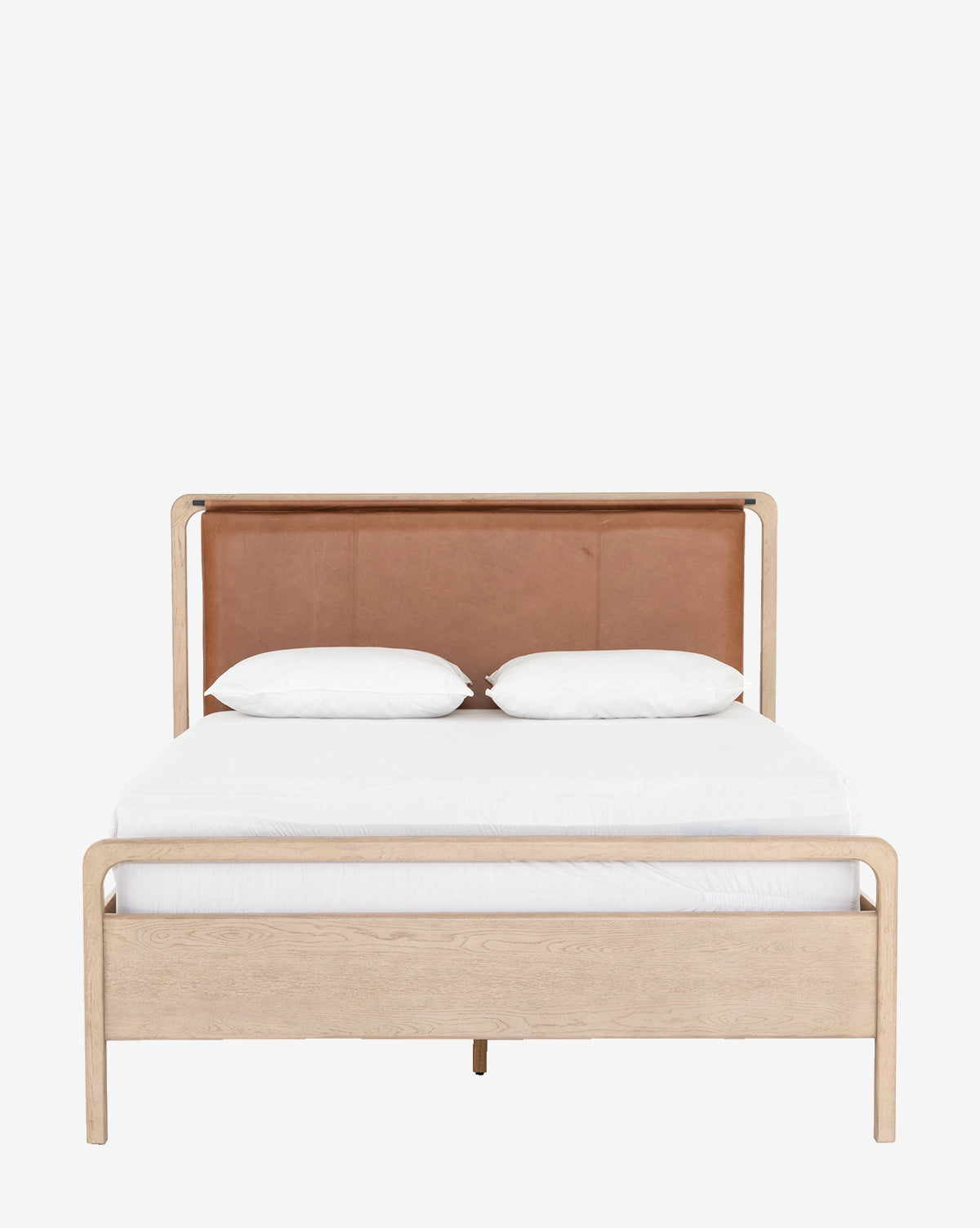 The Hensley Bed showcases a modern light wood frame, brown leather headboard, and white bedding with two plush pillows, all against a plain white background.