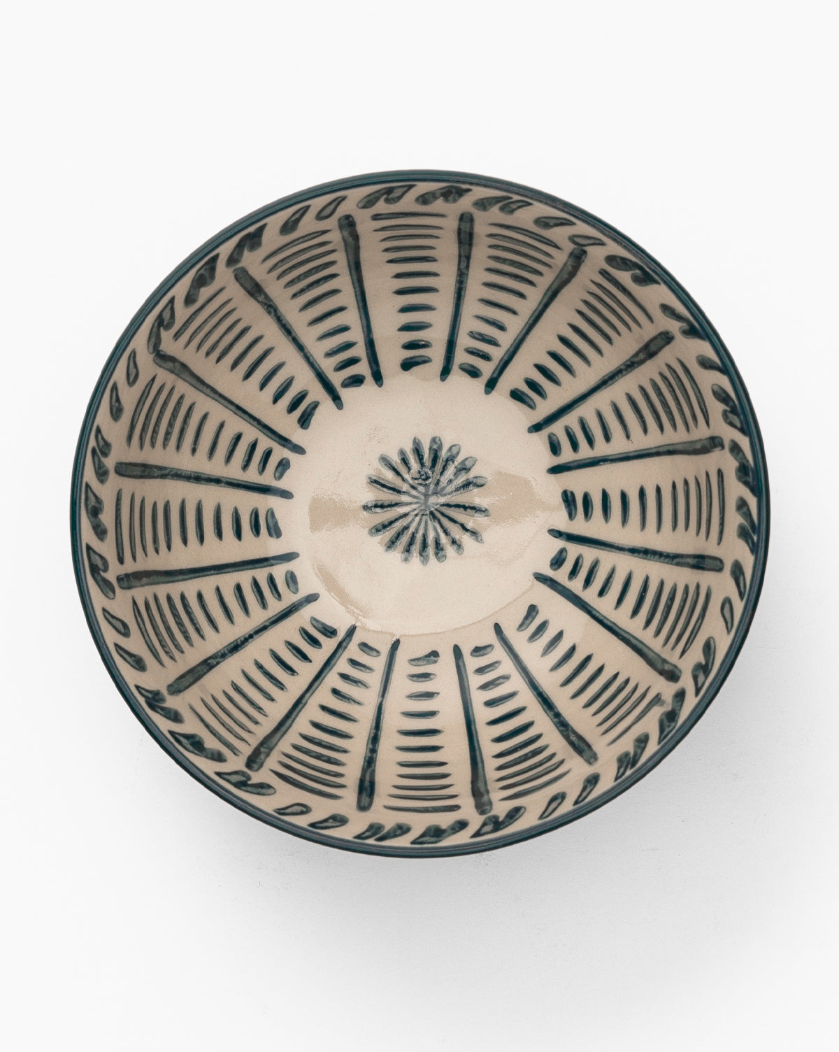 The Mattia Hand-Painted Bowl is a round, glazed stoneware piece with a cream-colored base and bold blue geometric patterns radiating from the center to the rim, by McGee & Co.