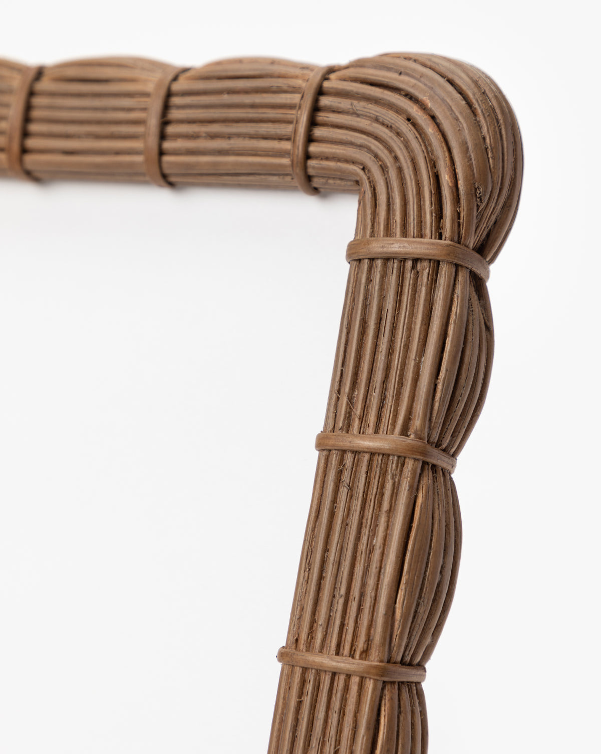 Close-up of the Hilde Woven Frame’s corner, showcasing its organic texture and curved design crafted from natural materials, set against a plain white background.