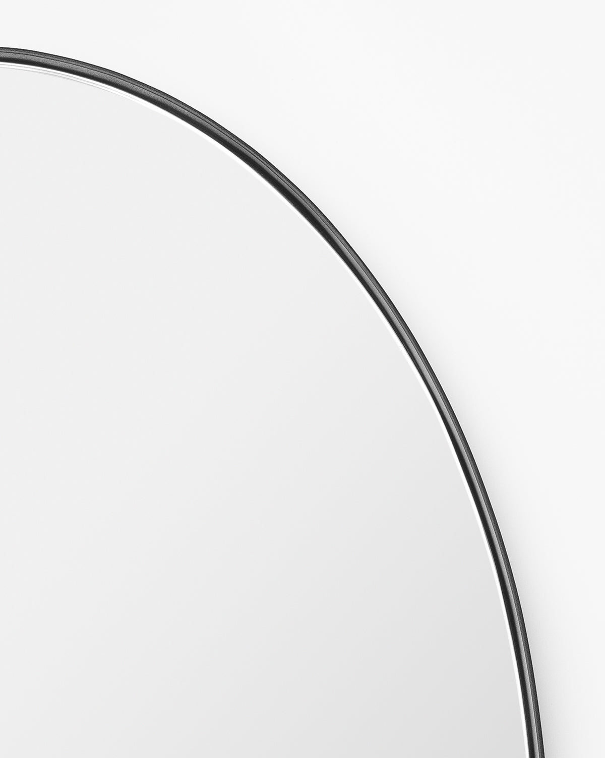 A close-up of the Hogan Oval Mirror showcases its sleek, thin stainless steel frame, with only the upper section visible against a plain white background, by McGee & Co.