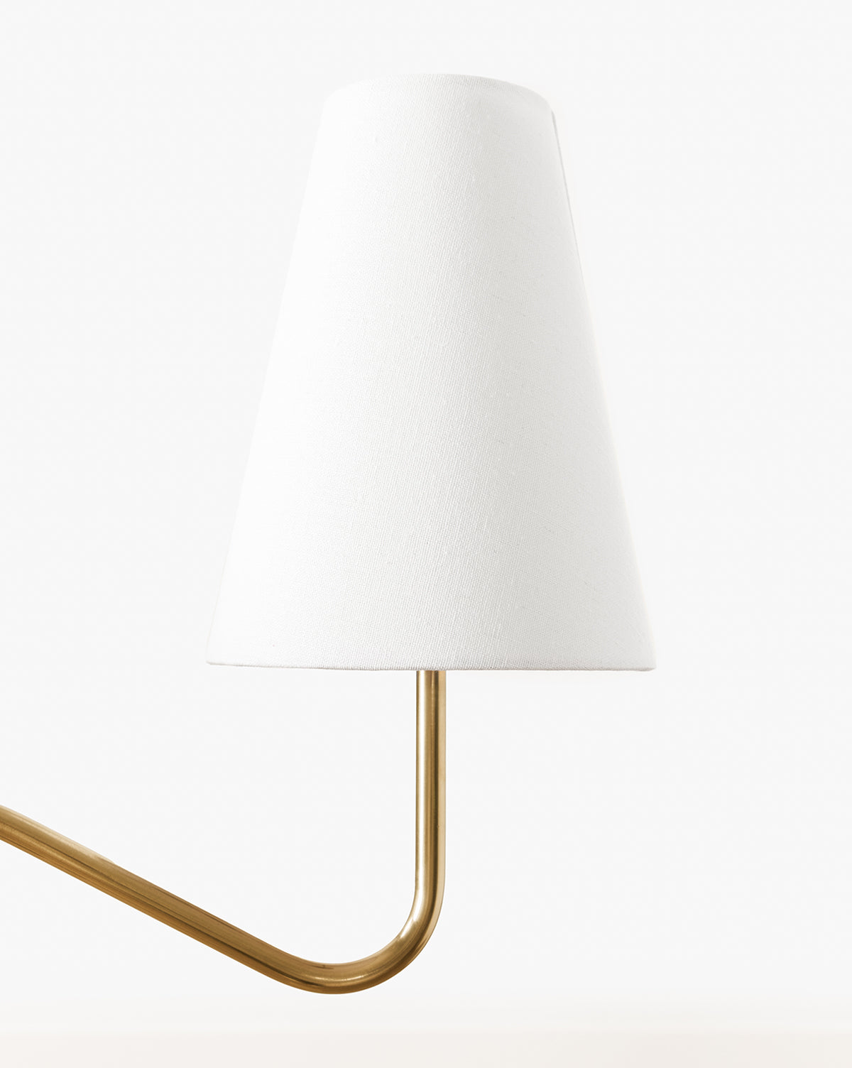 The Holloway Floor Lamp features a conical white shade and a curved antique brass arm, showcased against a plain white background, by McGee & Co.