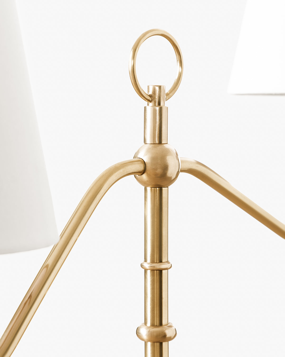 Close-up of the Holloway Floor Lamp in antique brass highlights its double-arm style, ring finial, and details of white lampshades, set against a plain white background by McGee & Co.