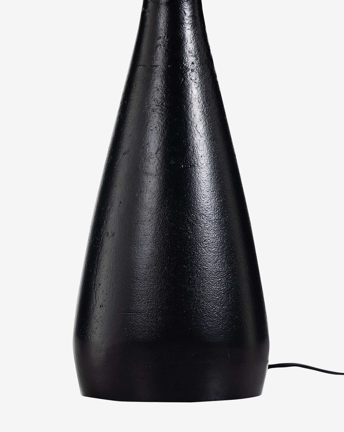 A close-up shows the base of the Innes Tapered Table Lamp, featuring a black textured cone shape on a white background. A rectangular mirror nearby reflects the thin black cord extending from the lamp’s lower right side, by McGee & Co.