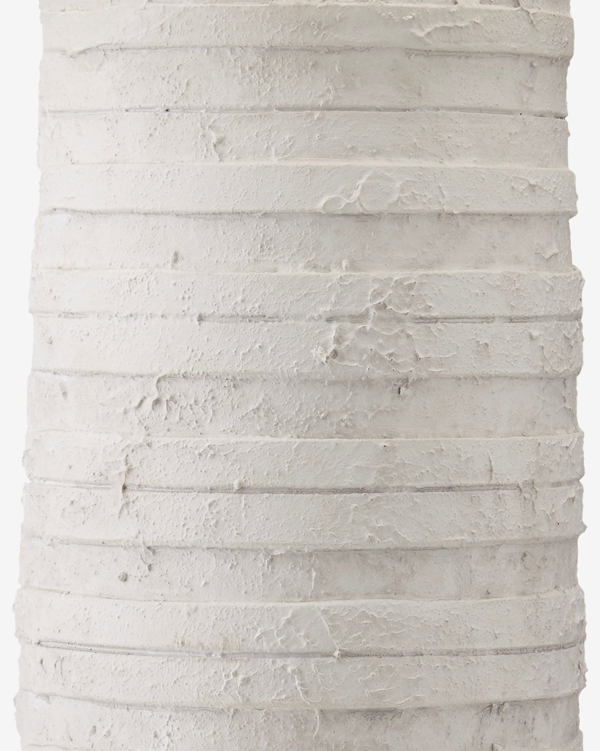 Close-up of a textured white surface with horizontal ridges and rough lines, resembling plaster or layers of thick paint—evoking the handcrafted look featured on the Innkeeper Table Lamp, by McGee & Co.