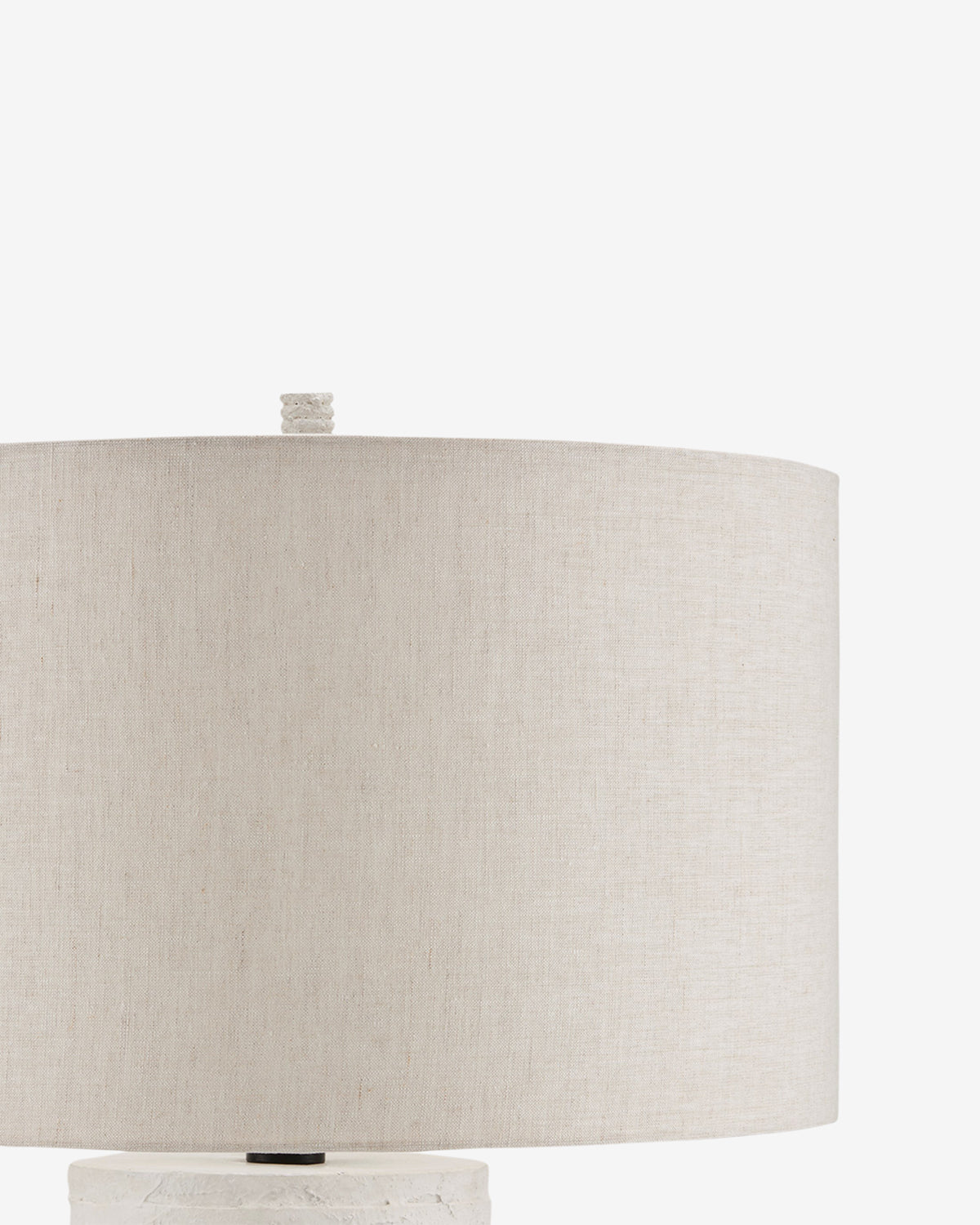 A close-up of the Innkeeper Table Lamp features a beige fabric shade with a small finial atop it, set against a white background. The visible base suggests its rustic design, characteristic of classic Innkeeper Table Lamps, by McGee & Co.