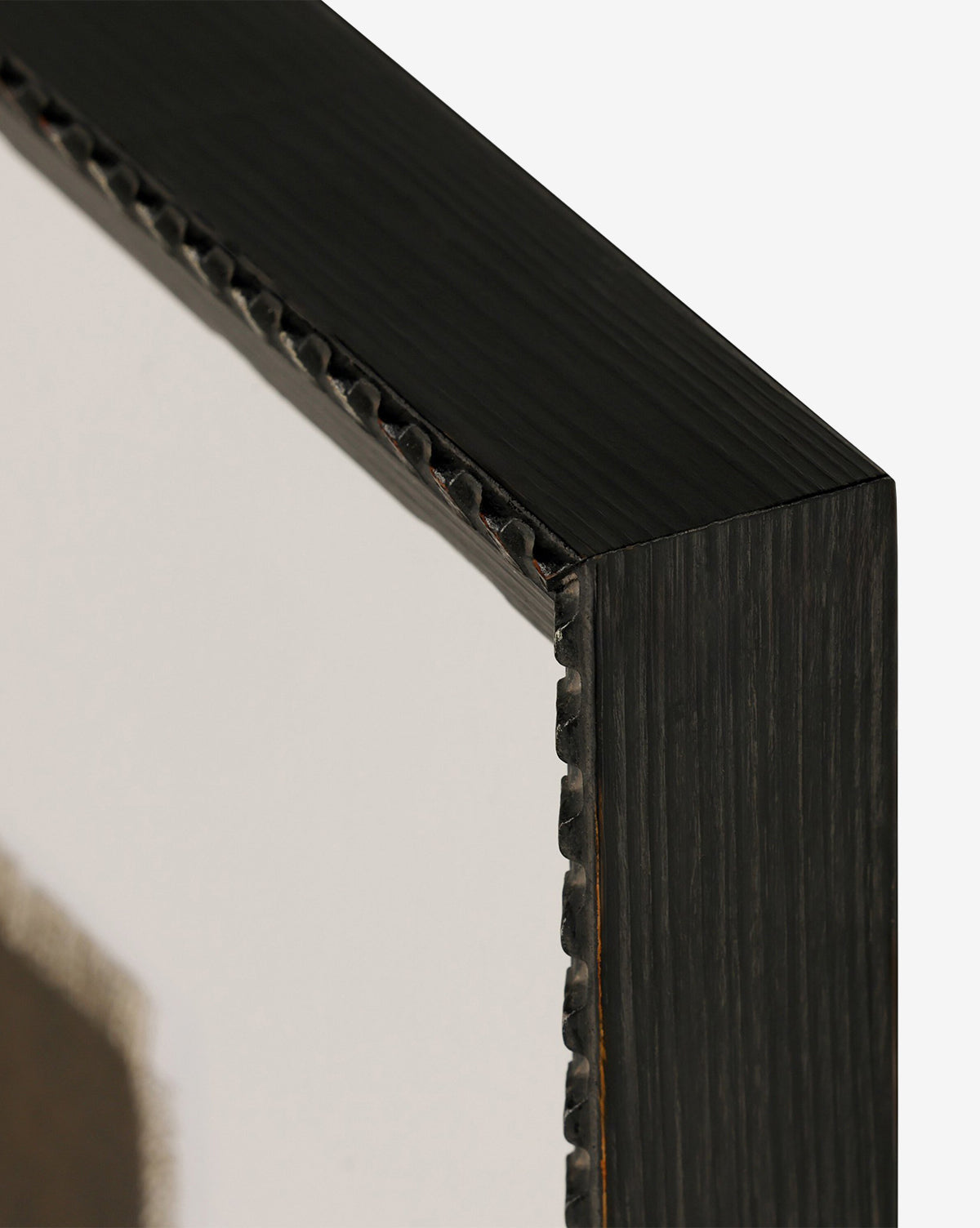 Close-up of a dark Brimfield black frame corner with a ridged edge, displaying part of the layered oil painting Iron and Brass by Bethany Joseph against a plain white background, by McGee & Co.