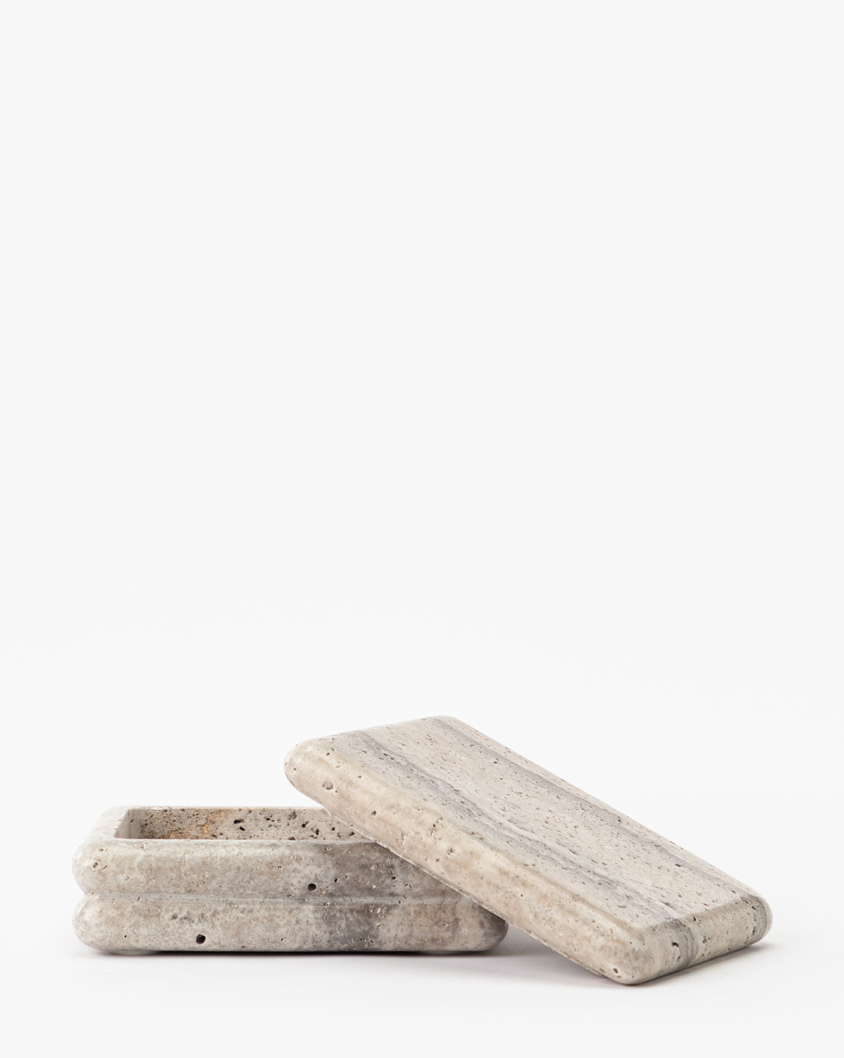 The Ives Stone Box, a rectangular shallow stone container with a matching lid, sits stylishly tilted and partially open, making for an elegant decorative accent against a plain white background.