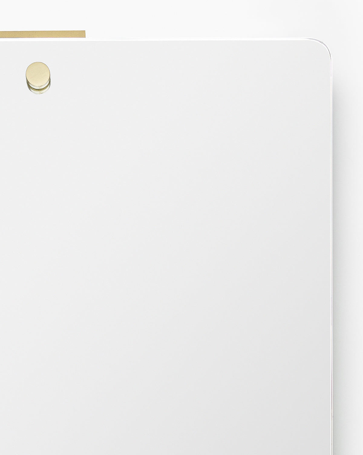 A minimal white magnetic dry erase board with rounded corners and a single gold magnet near the top left, designed to complement the Jacob Rectangular Mirror or a brass frame, placed against a plain white background, by McGee & Co.