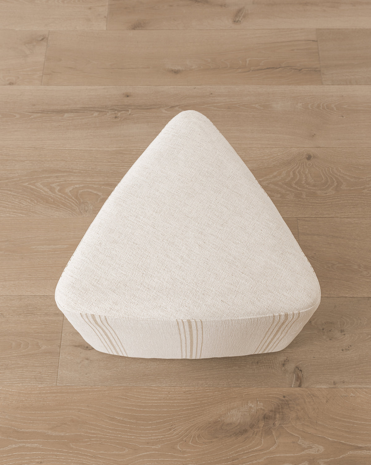 The Jacques Ottoman by Dongguan City Baby Furniture Co., Ltd features a triangular design, cream Crypton striped upholstery, and sits on a light wood floor—ideal for bringing stylish durability to kids’ rooms. McGee & Co.