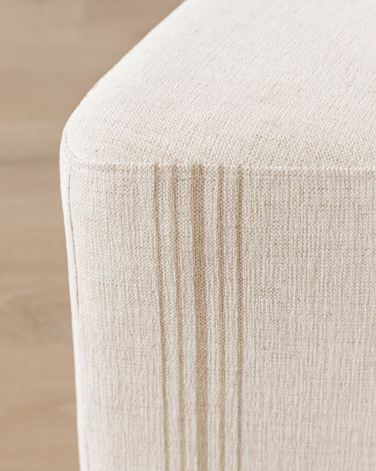 Close-up of a beige Jacques Ottoman by Dongguan City Baby Furniture Co., Ltd in Crypton striped fabric with vertical stitched lines, set on a wooden floor—ideal for stylish durability in kids’ rooms, McGee & Co.