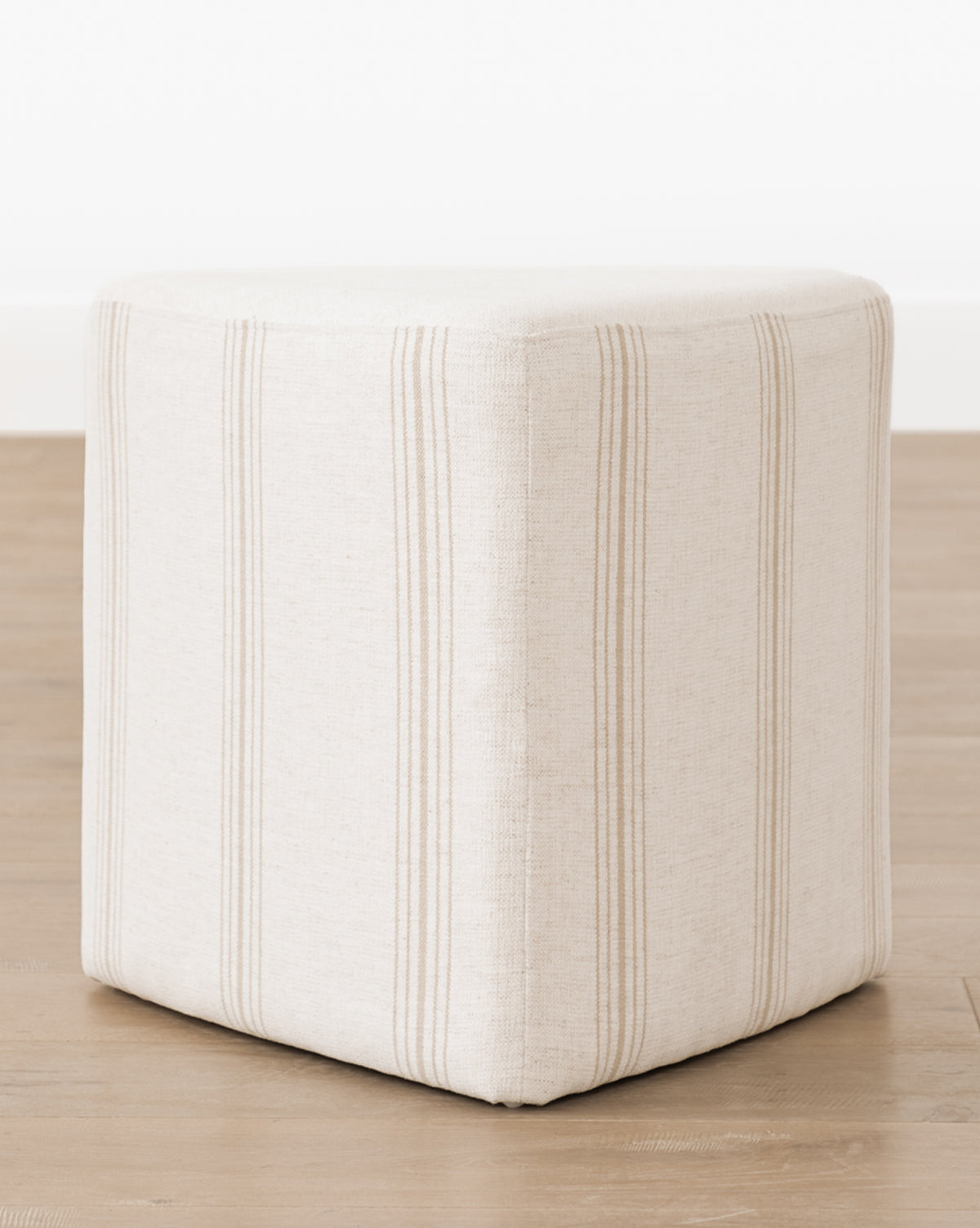 The Jacques Ottoman by Dongguan City Baby Furniture Co., Ltd features cream crypton striped fabric with subtle beige lines—ideal for kids’ rooms or modern spaces, and pairs beautifully with a light wood floor—McGee & Co.