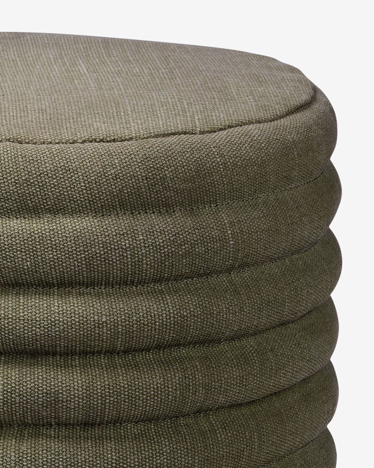 Close-up of the Made Goods Jefferson Stool, a round quilted design in olive green with textured fabric, horizontal stitched seams, and a soft cushioned top, shown against a white background. McGee & Co.
