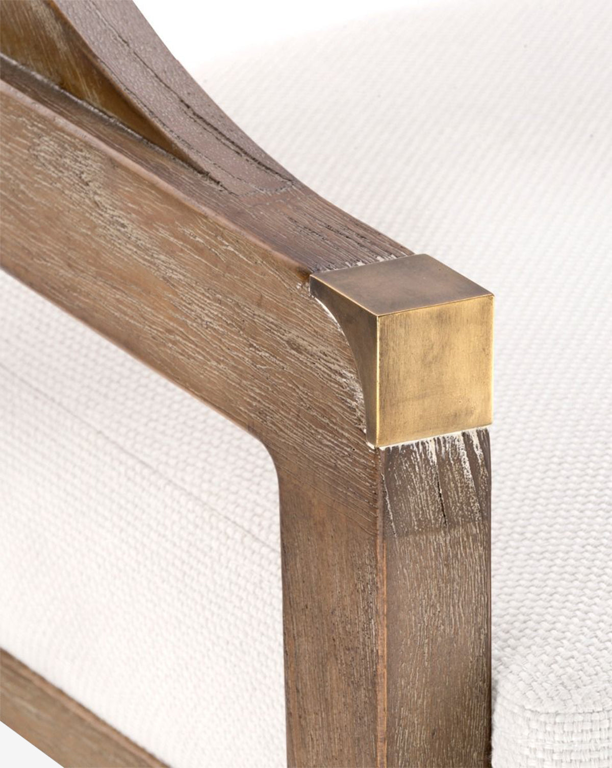 Close-up of the Jensen Counter Stool’s wooden armrest with a brass accent. The stool showcases textured white upholstery, a natural wood finish, and a hand-woven cane back made from solid Cape Lilac Mahogany, by McGee & Co.
