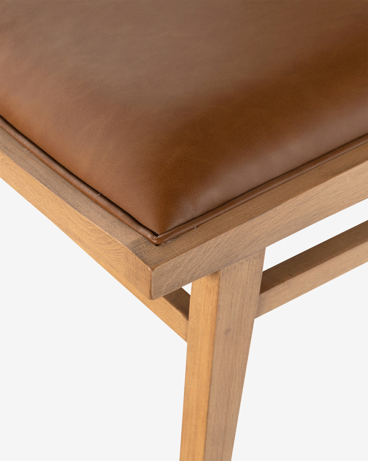 Close-up of the Jett Dining Chair, showcasing its sturdy beech wood frame and padded seat upholstered in smooth brown leather or faux leather, by McGee & Co.