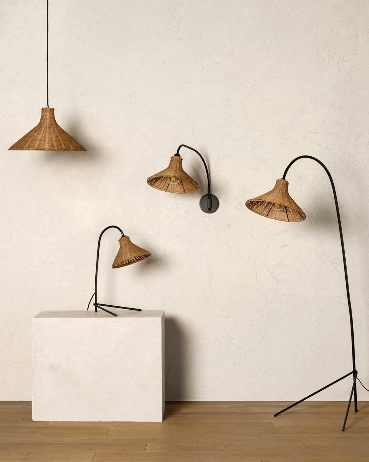 Four Johanson Woven Floor Lamps with black metal stands are showcased: a pendant lamp hangs from the ceiling, a wall lamp is mounted, and two Johanson Woven Floor Lamps of varying heights stand beside a white block on a wooden floor, by McGee & Co.