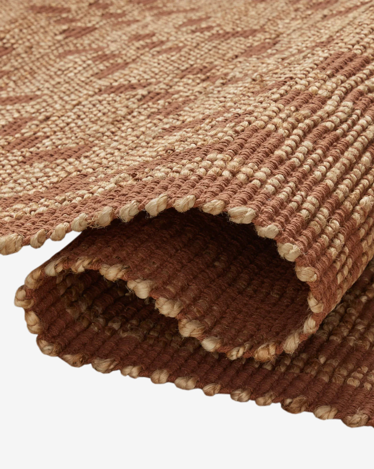 A close-up of the Judy Spice Jute Rug Collection No. 7 shows its rolled, handwoven brown and beige design with a textured surface and thick, sturdy fibers—ideal as a durable, neutral accent rug for any space, by McGee & Co.