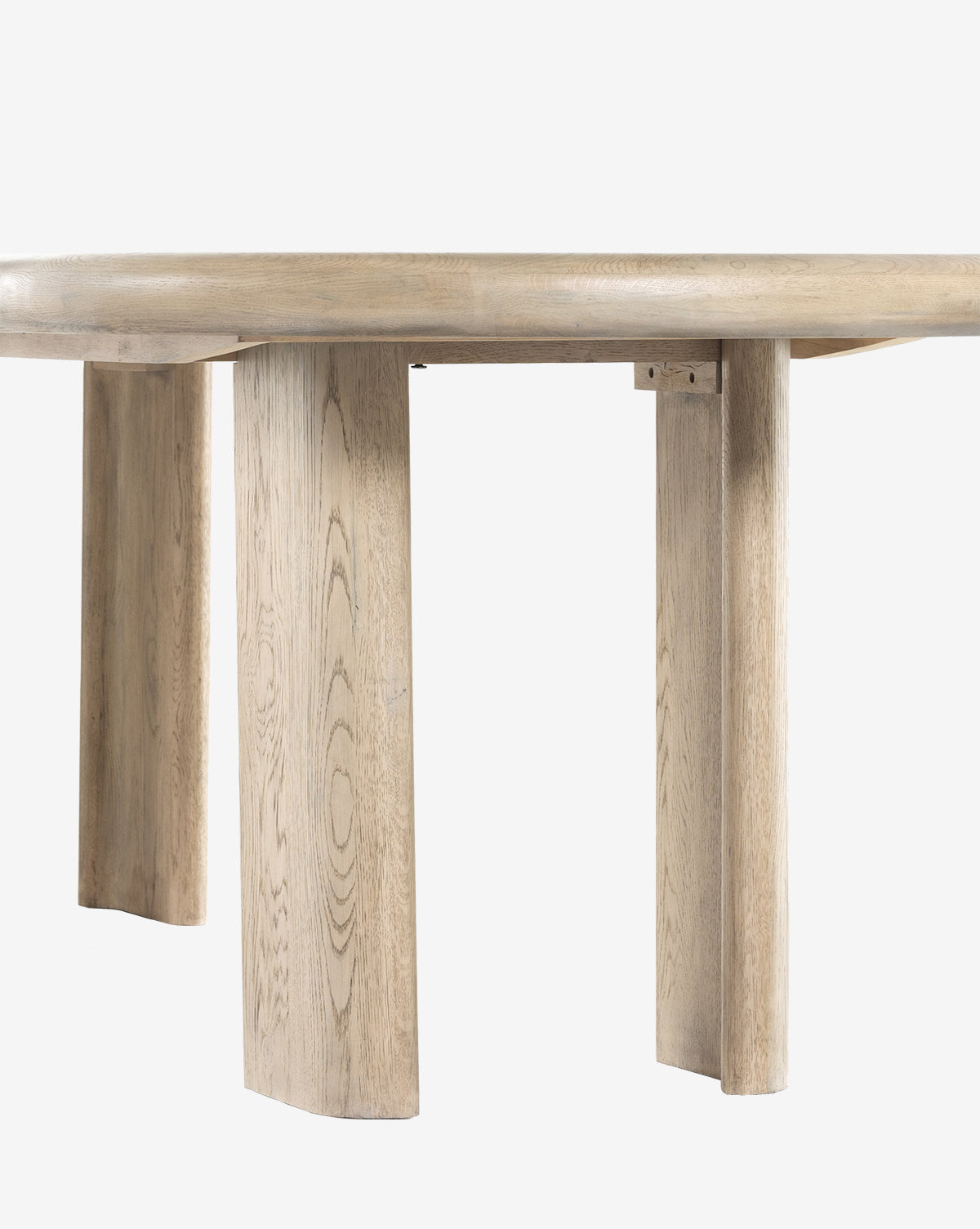 A close-up of the Juliana Extension Dining Table reveals its round solid oak top and three wide, flat legs with natural wood grain, highlighting modern design against a plain white background by McGee & Co.