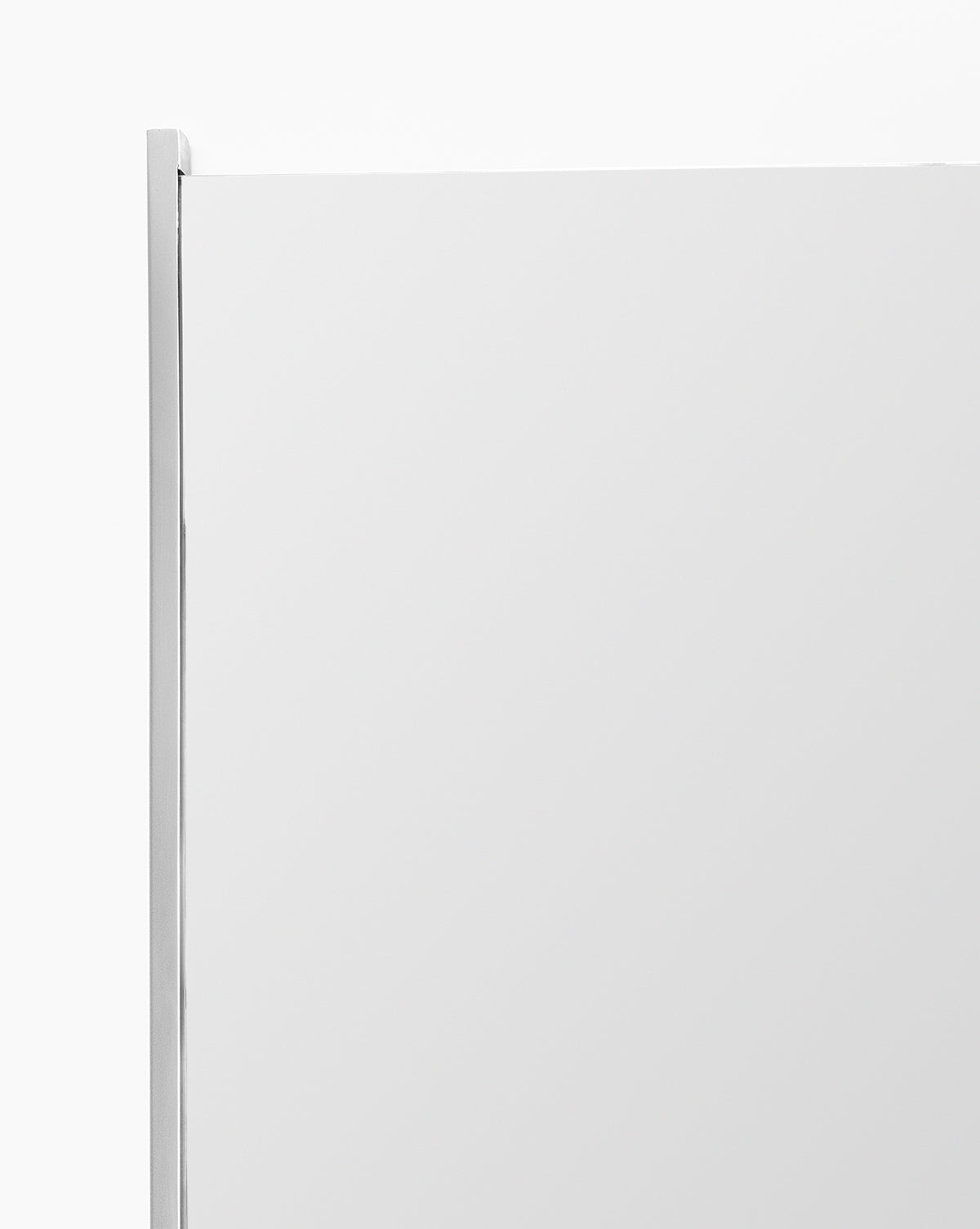 A close-up of the top corner of the Julie Mirror, a rectangular bathroom mirror with a thin polished nickel frame, set against a plain white background, by McGee & Co.